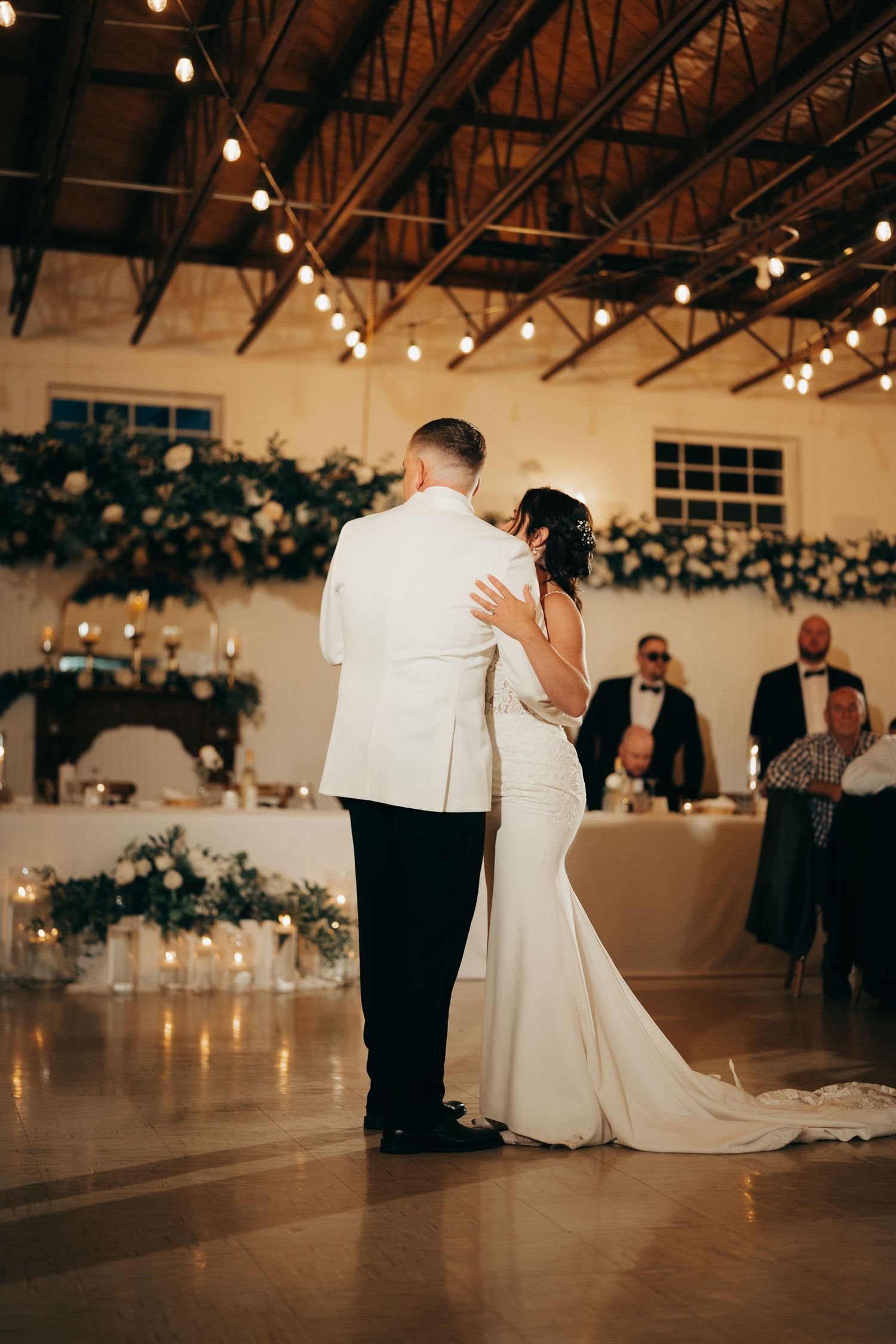 A romantic first dance between newlyweds at a wedding reception with string lights and candles creating an intimate atmosphere.