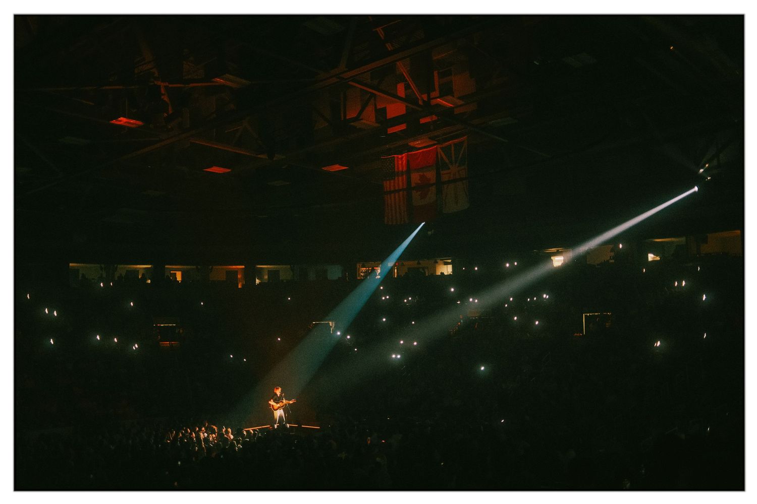 Glowing red and blue lights illuminate a dark concert venue with dramatic stage lighting effects.