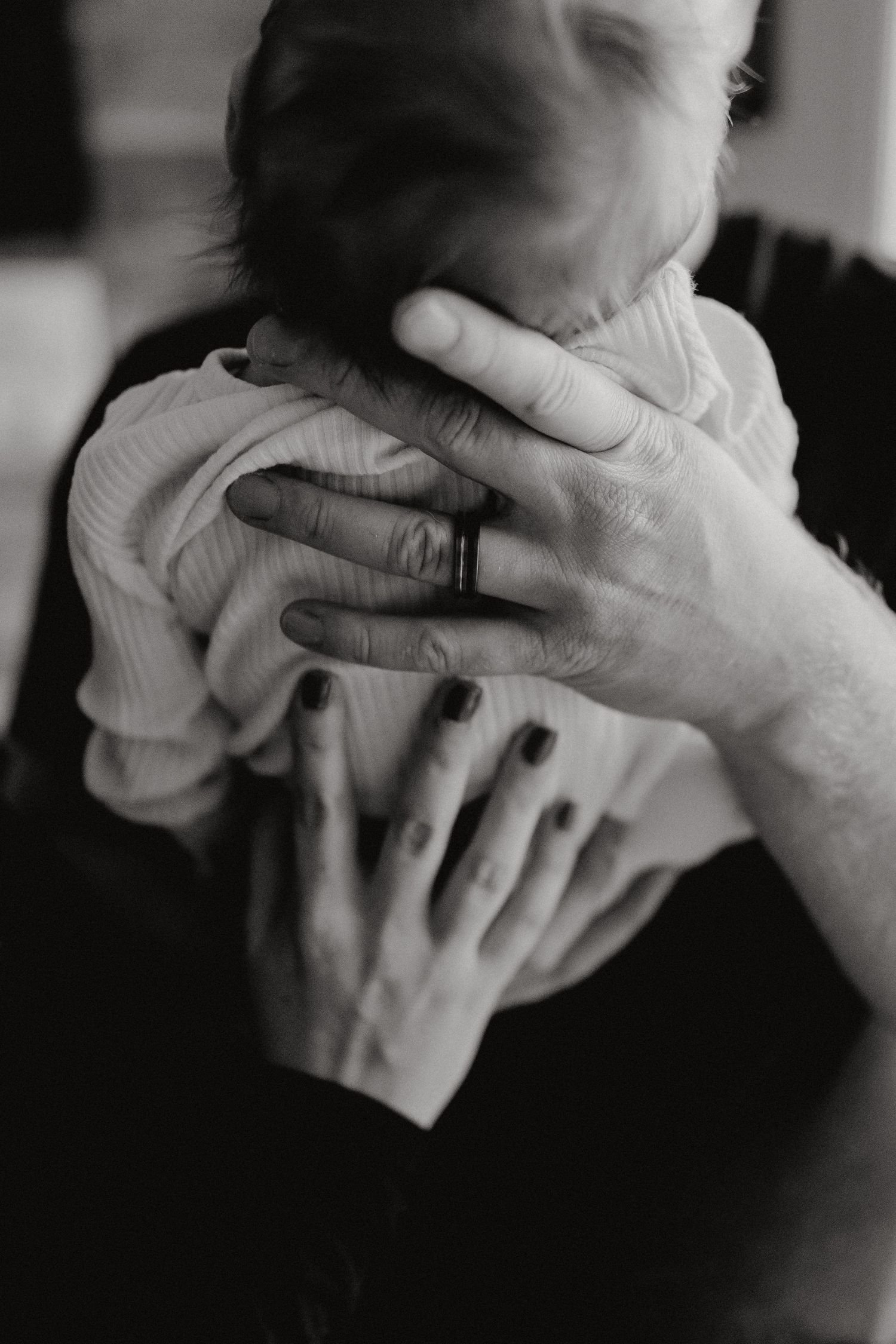 Close up view of hands cradling a baby wrapped in white cloth.