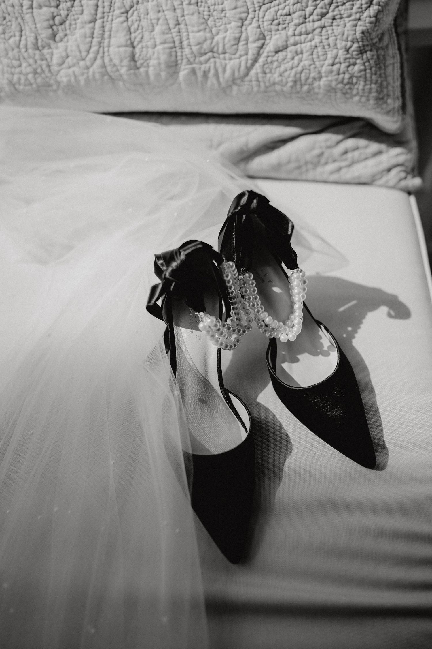 Elegant black bridal shoes with sparkle details displayed against white wedding dress fabric.