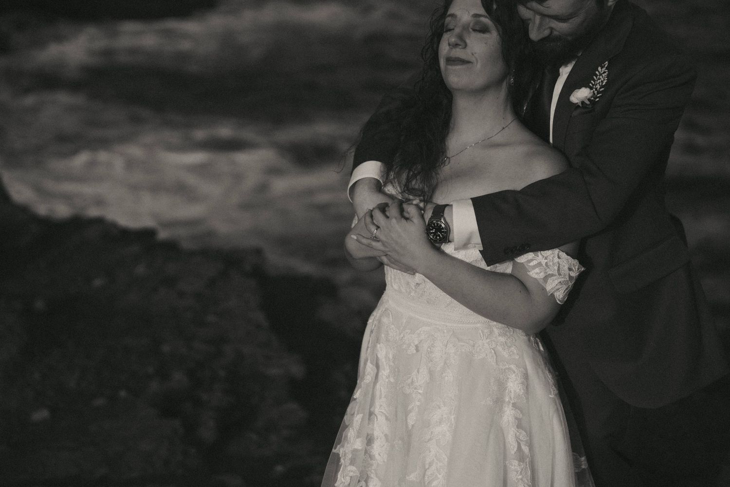 Intimate black and white wedding portrait captured against moody sky.
