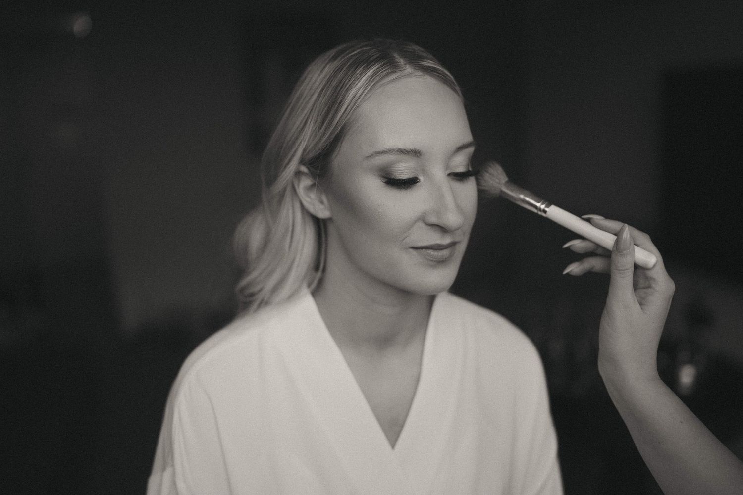Artistic black and white photo of wedding day makeup session in natural light.