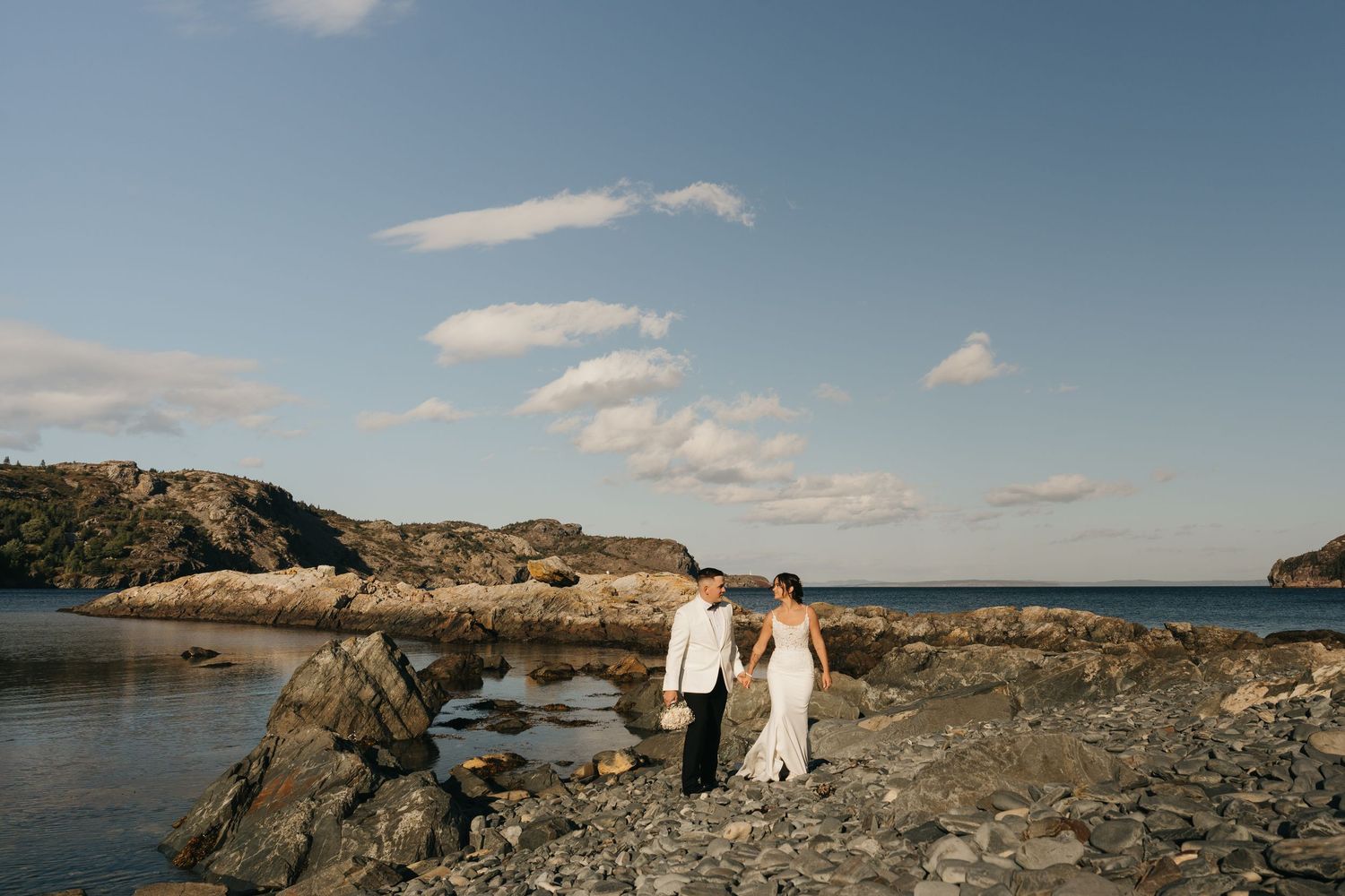 Panoramic view of a rocky coastal landscape with blue skies and scattered clouds on a sunny day.