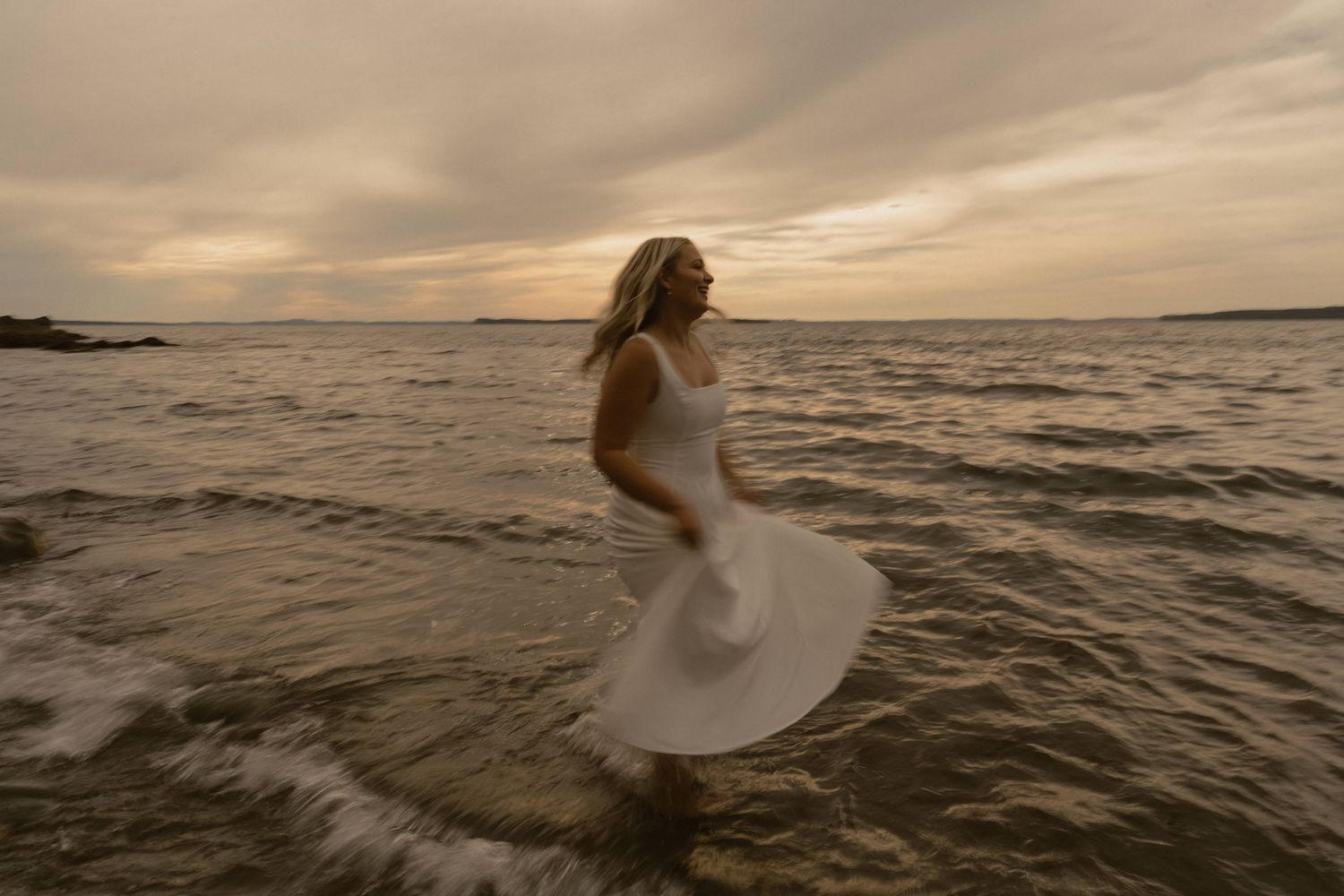 A romantic beach scene at dusk with silhouettes against the moody ocean and cloudy horizon.
