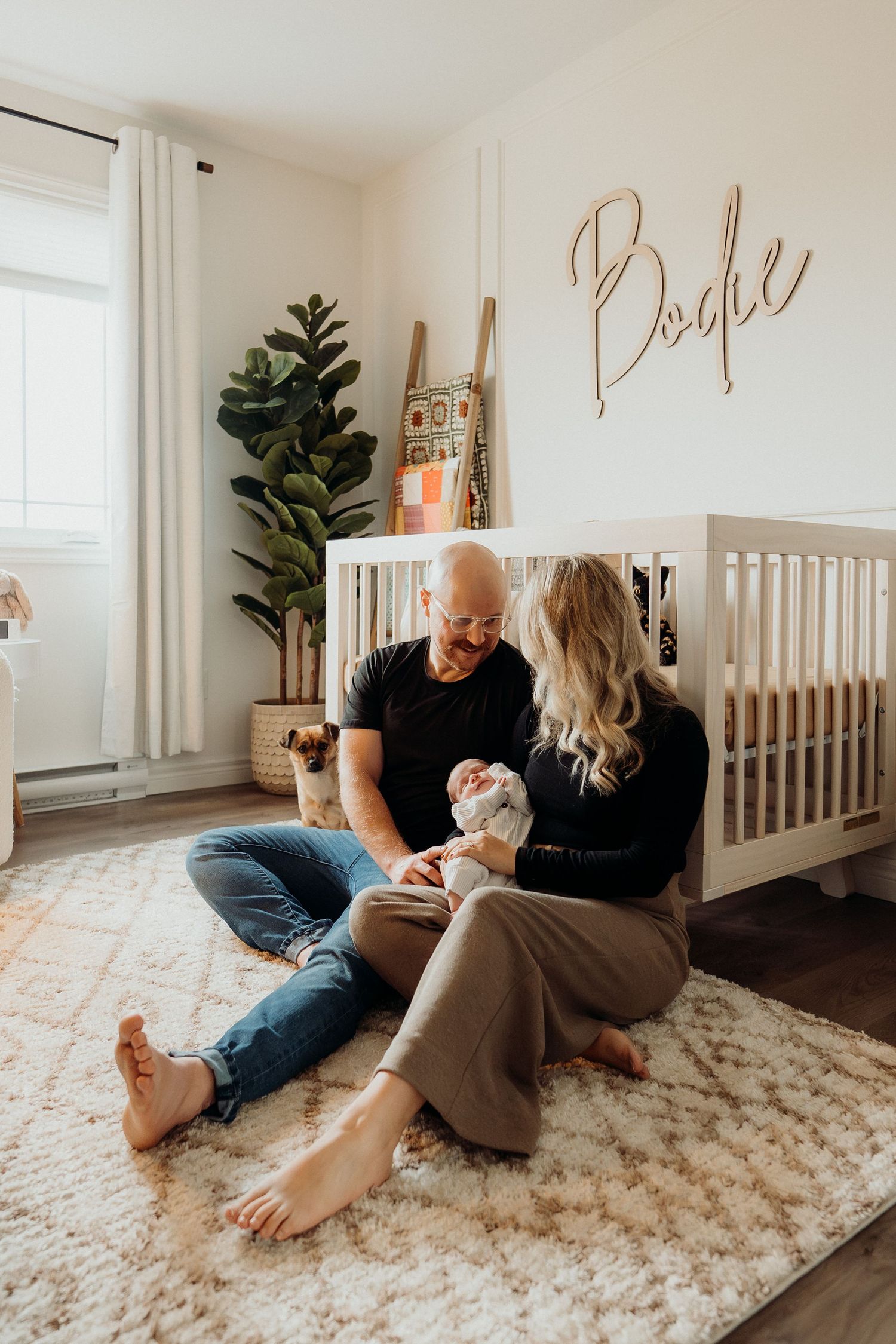 Family relaxing together on a plush carpet in a minimalist nursery room.