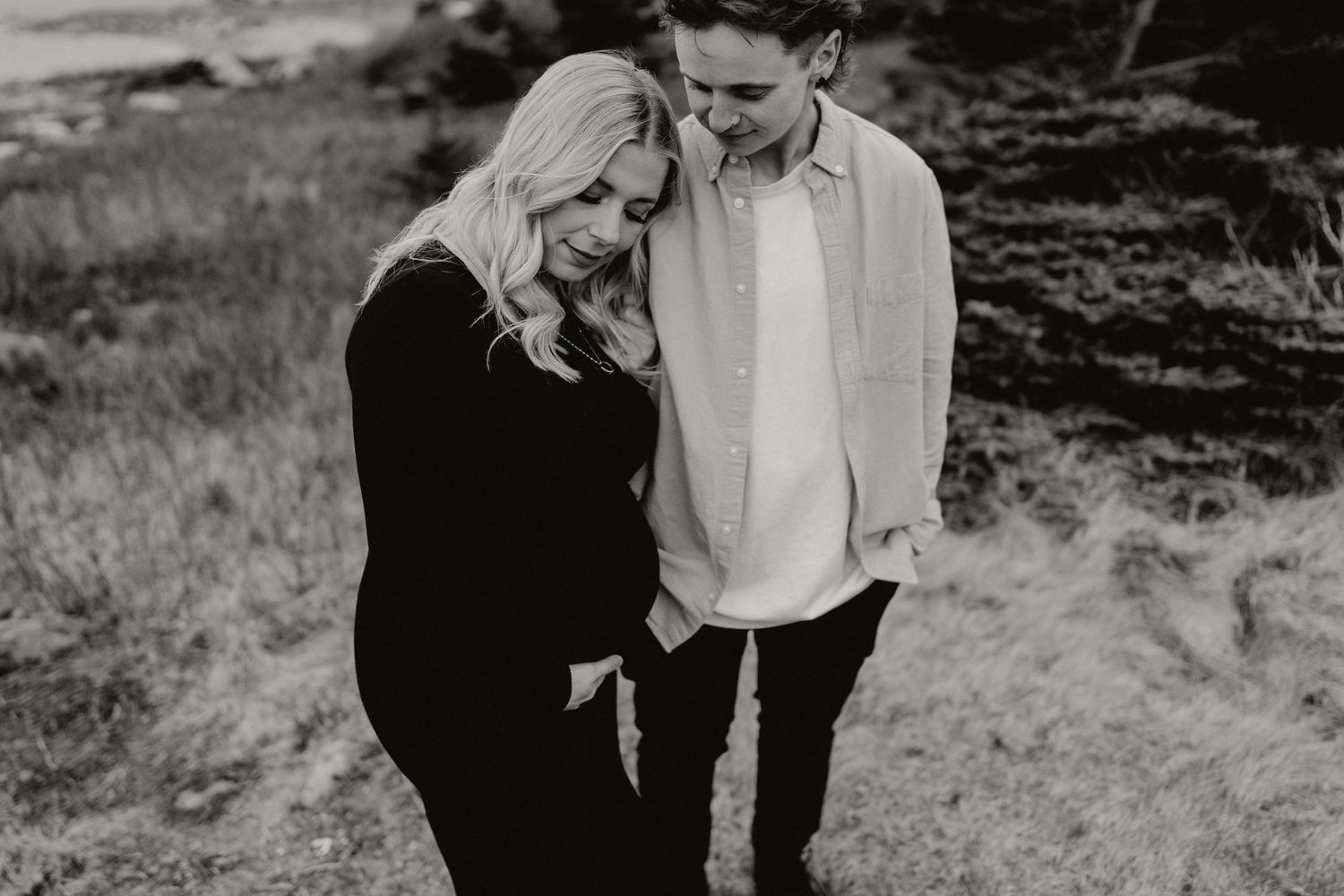Black and white intimate maternity portrait on a rugged outdoor landscape.