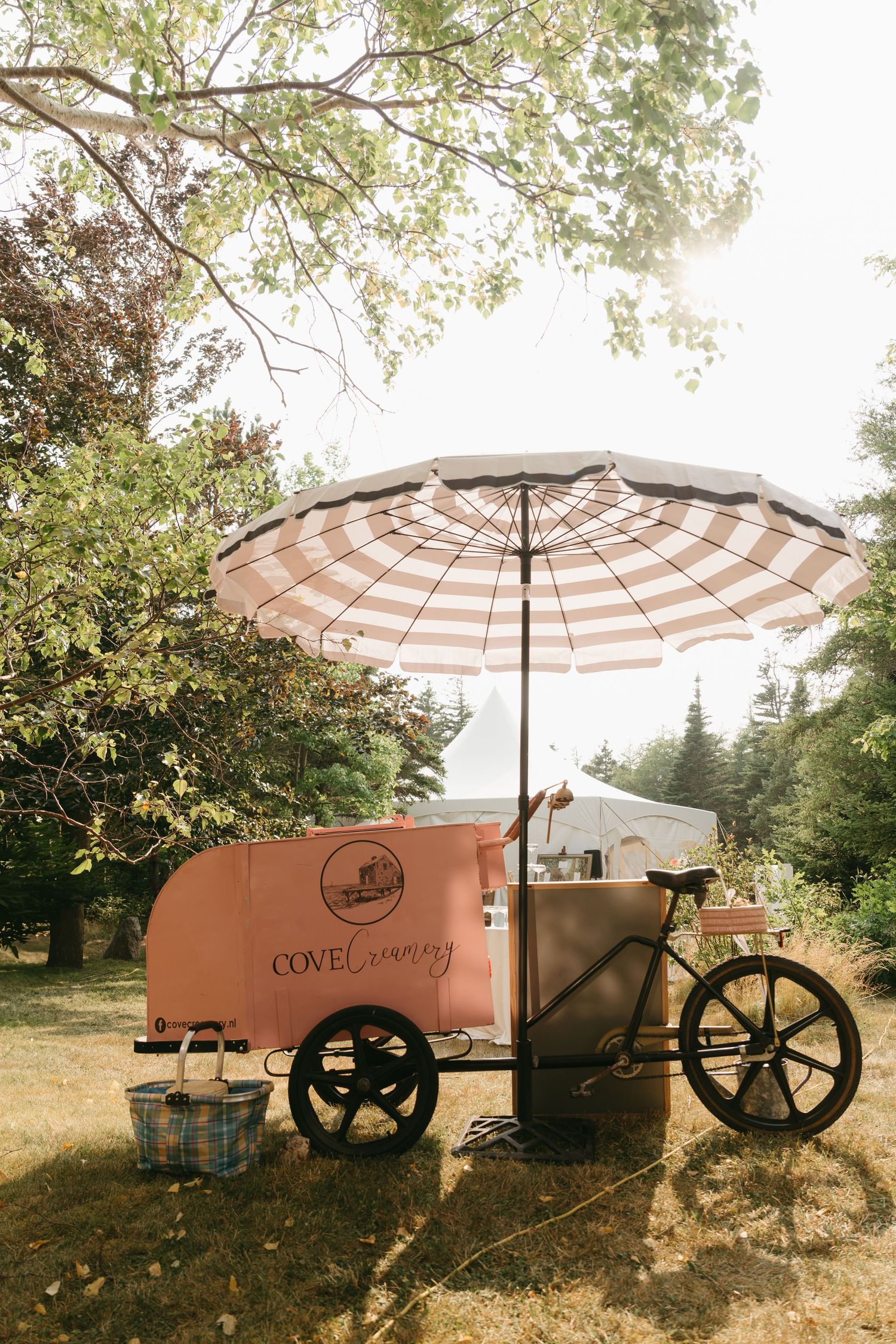 Vintage style food cart with striped umbrella in an outdoor garden setting.