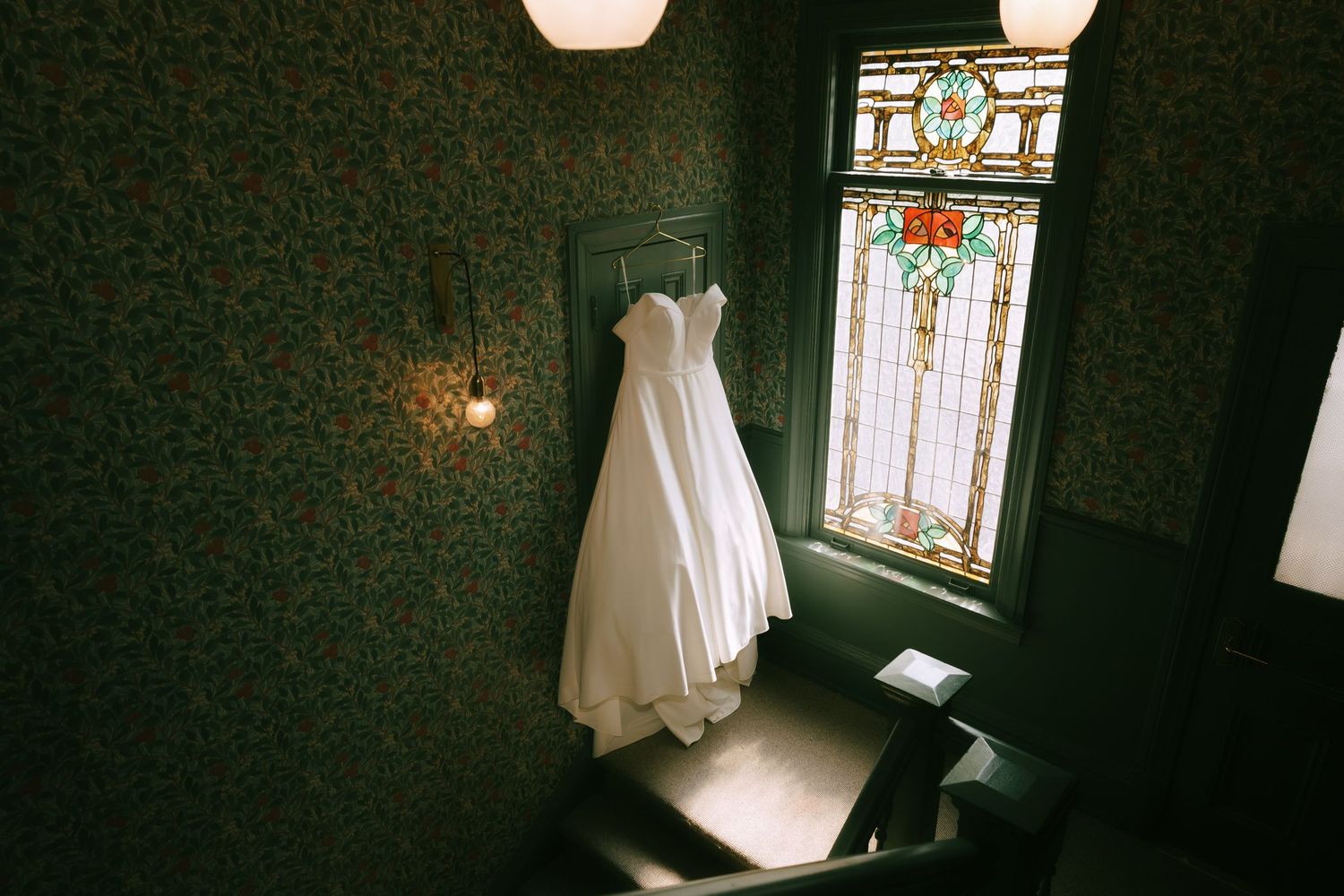 Dark room interior with pendant lights and white curtains hanging by stained glass windows.