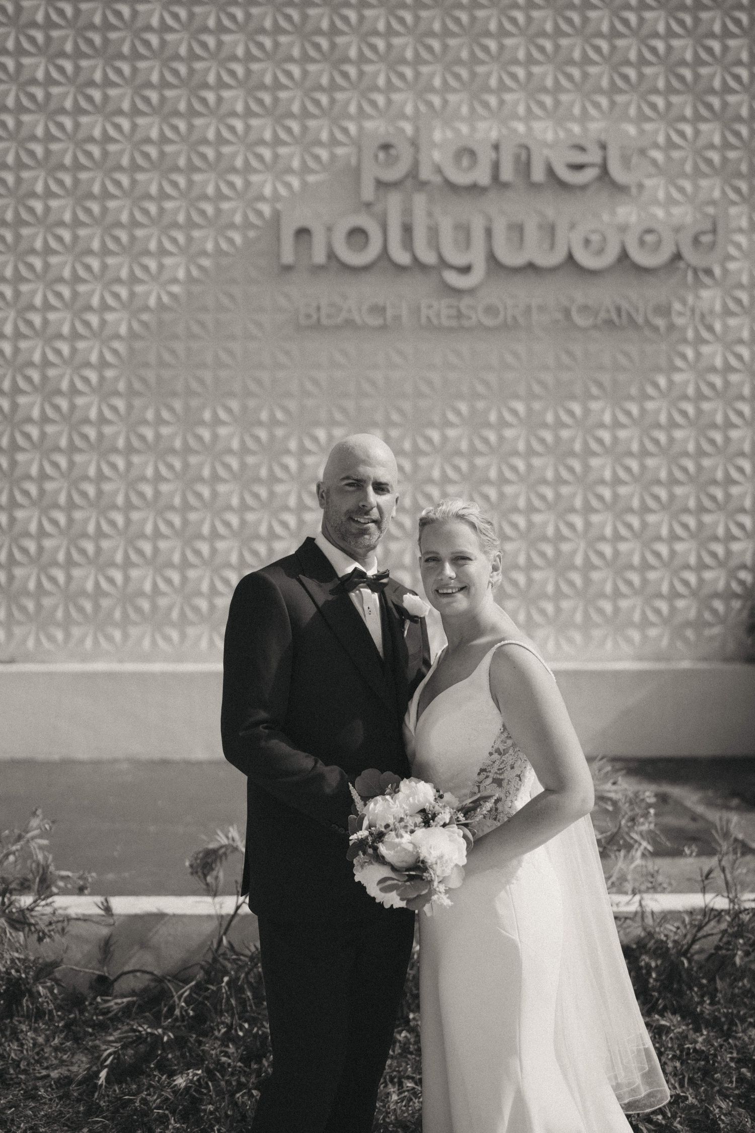 A couple pose for wedding photos against a textured wall with Hollywood Beach Resort signage.