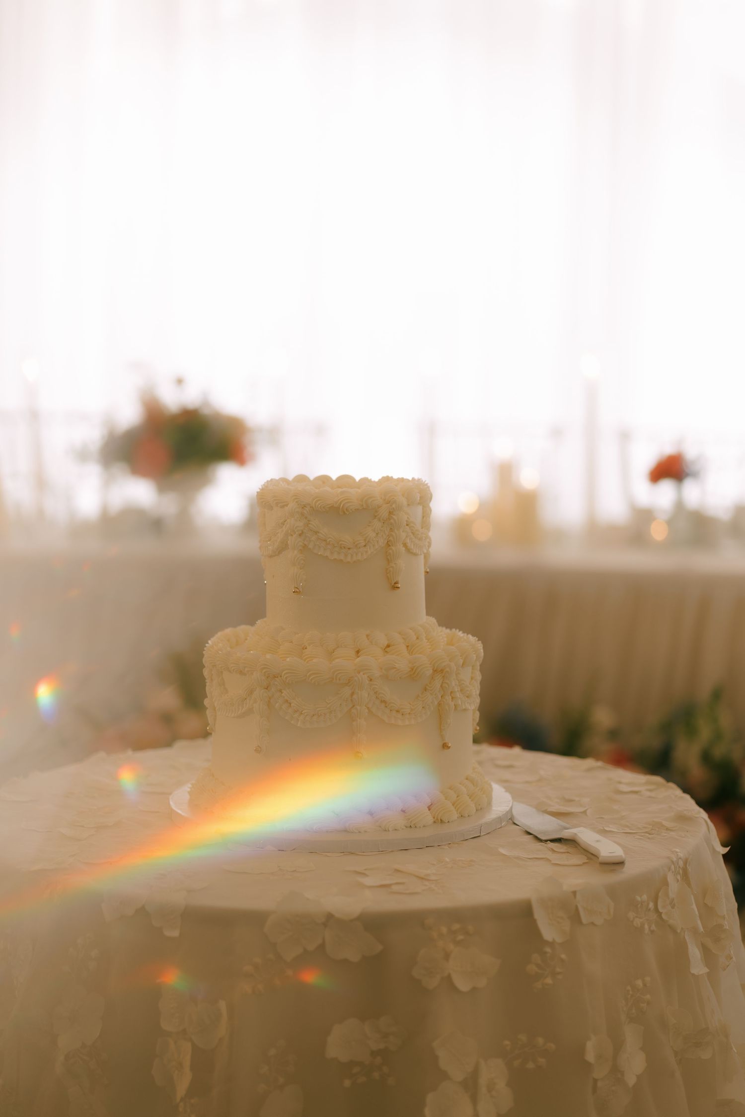 A decorative white wedding cake creates a rainbow prism effect in the ambient lighting.
