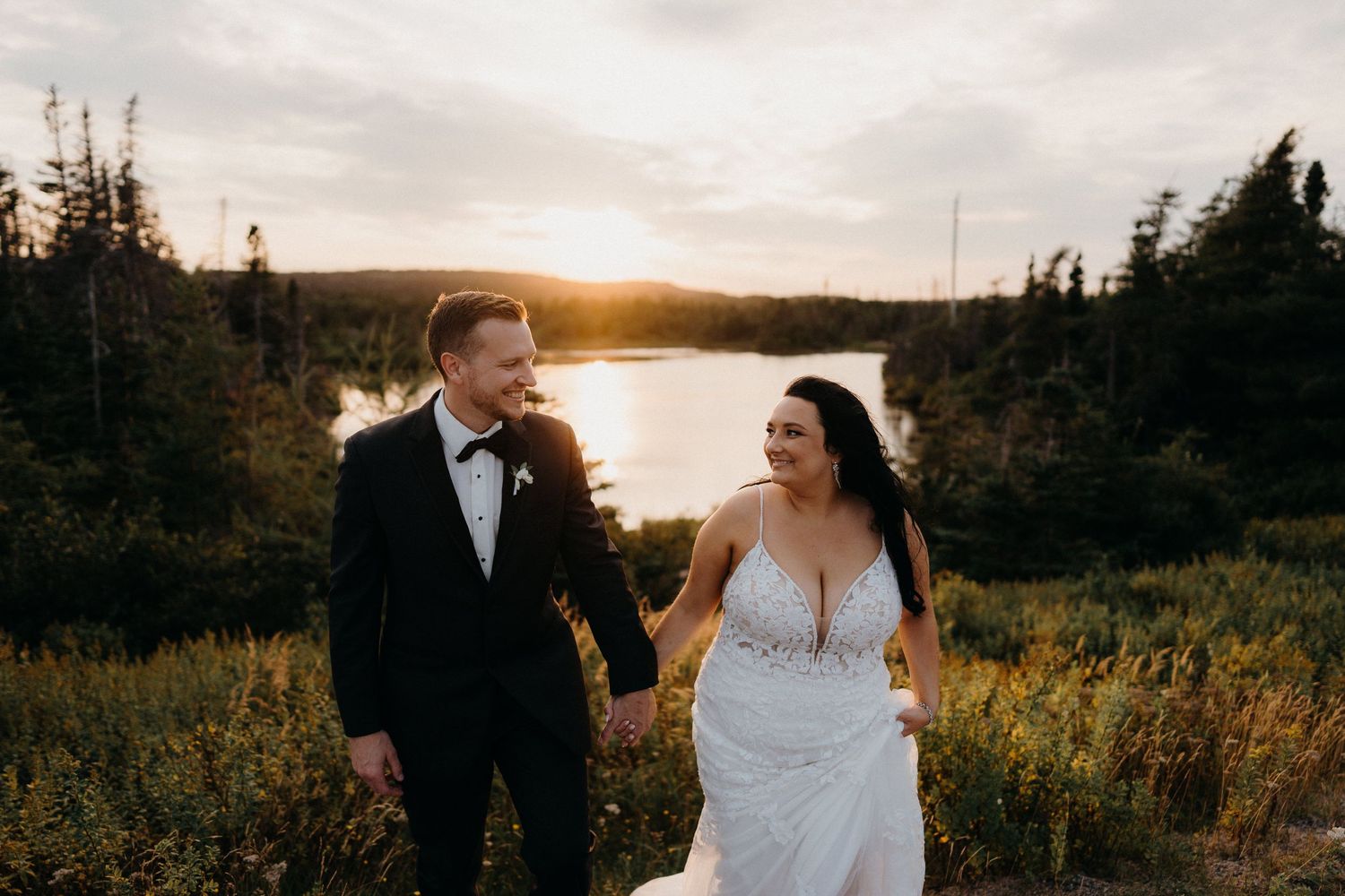 Couple walking through scenic meadow during golden hour sunset.