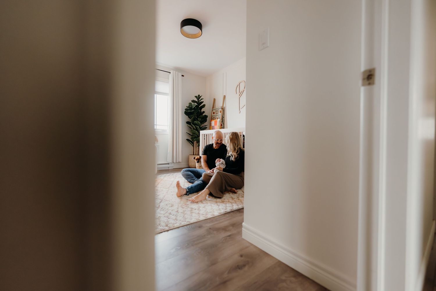Sunlit hallway scene with a gentle moment between caregiver and infant.