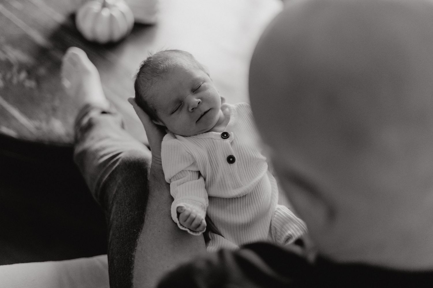 Side view of infant wearing white buttoned sweater during peaceful moment.