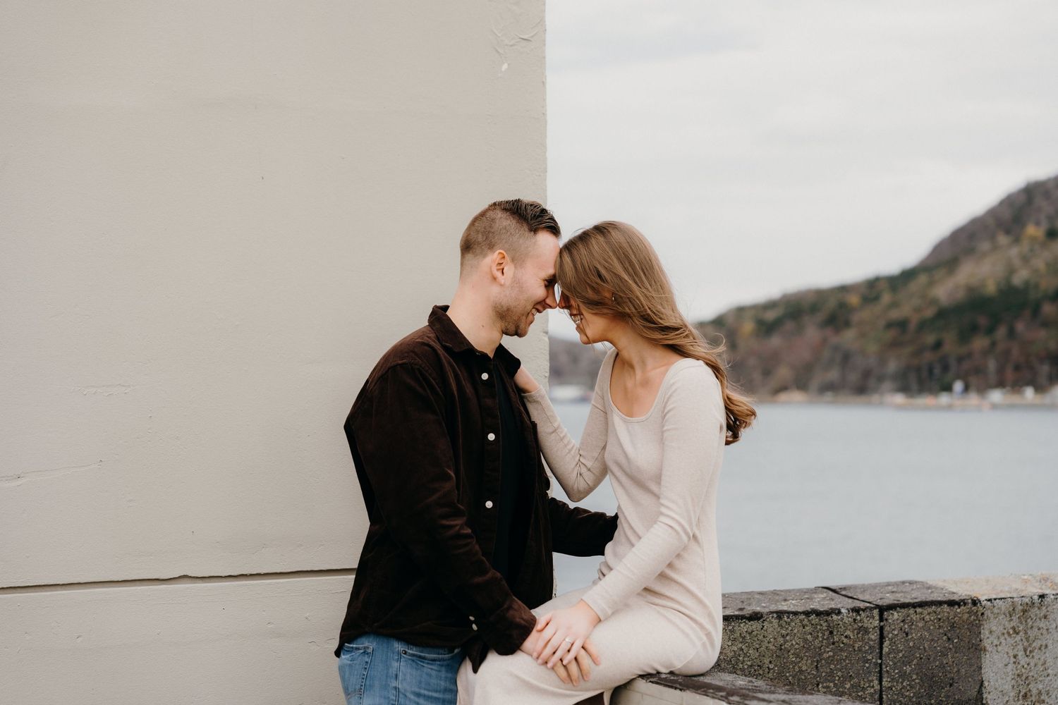 A tender moment between a couple during an outdoor photoshoot near the water.