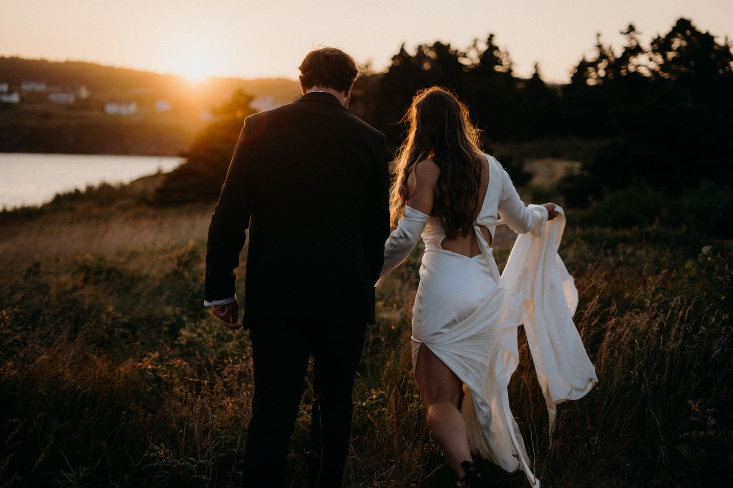 Couple walking together during sunset in a scenic outdoor field with warm golden light.