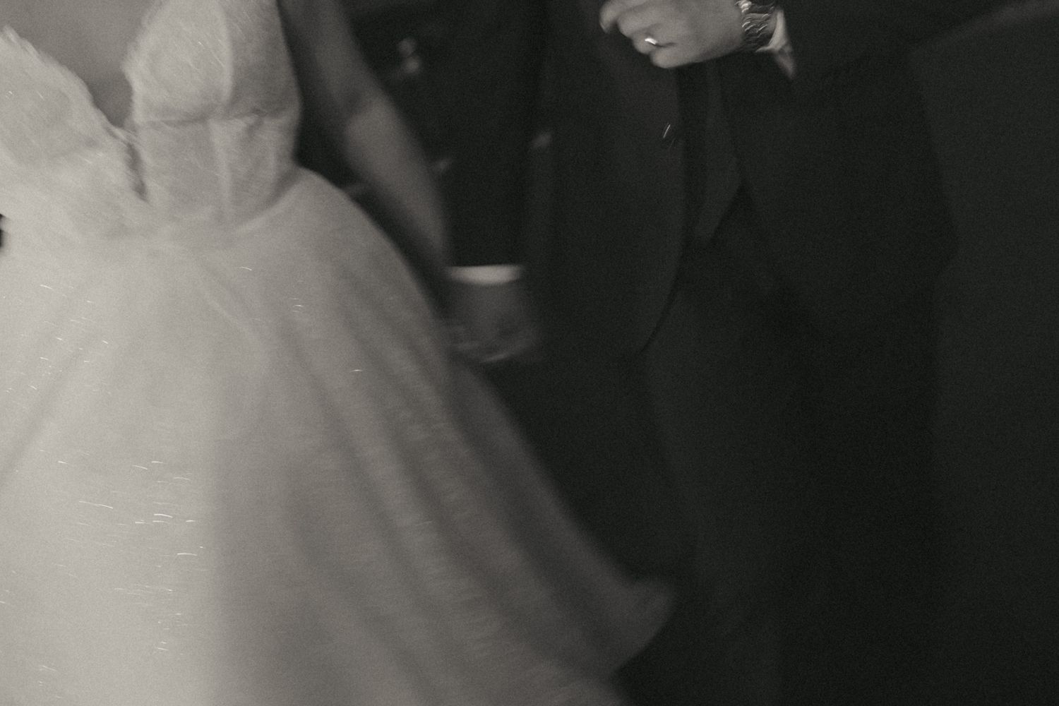 A black and white photograph shows a person wearing a white dress with lace details and a veil.
