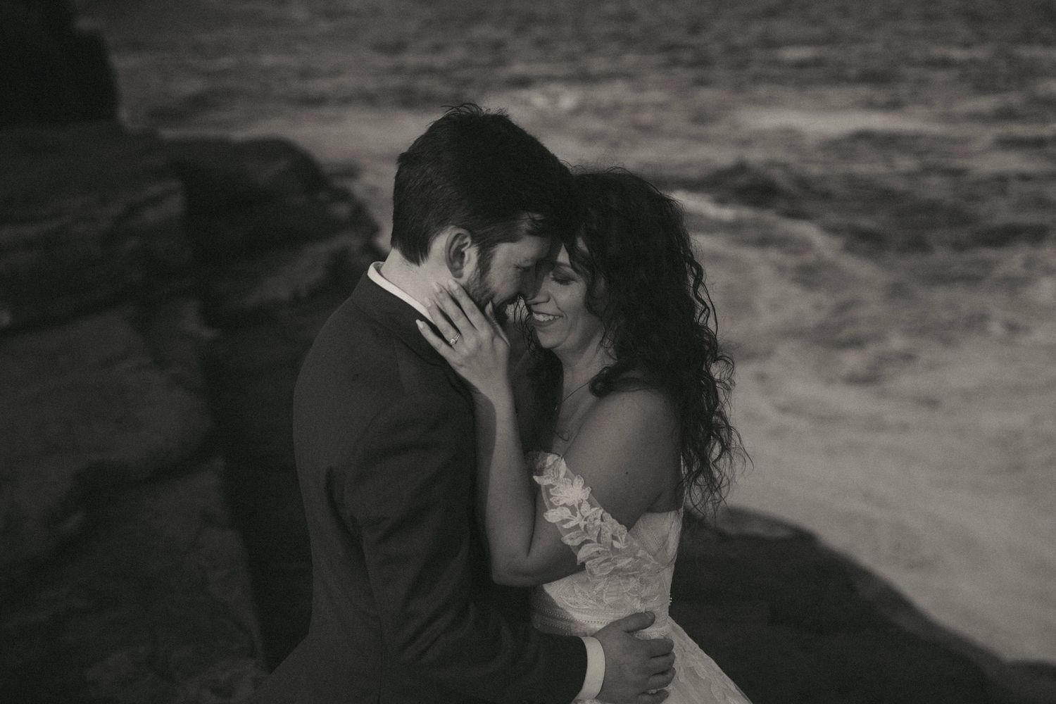 Intimate seaside wedding moment captured in dramatic black and white.
