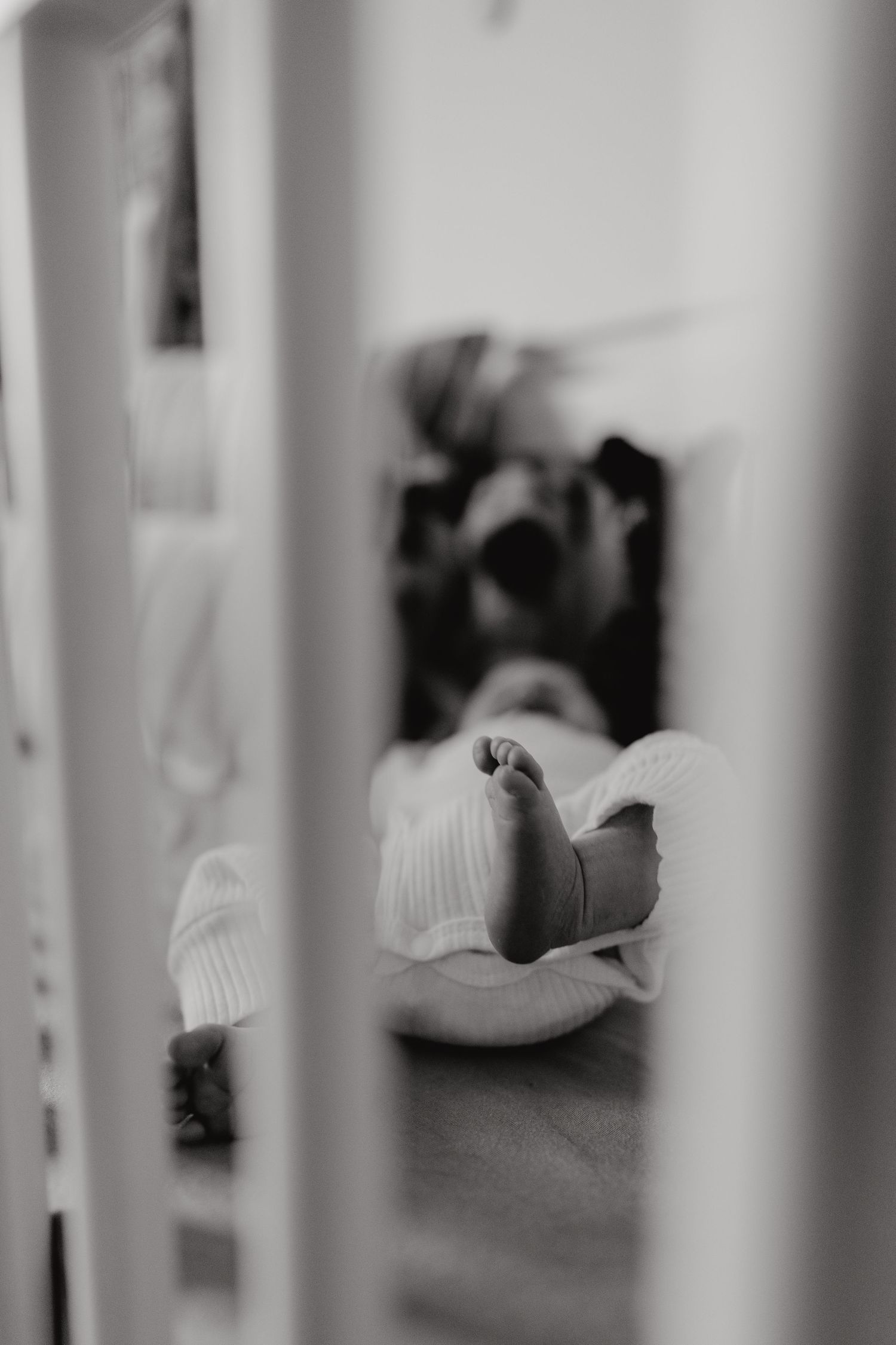 Black and white image showing bars of a crib in sharp focus with blurred background.