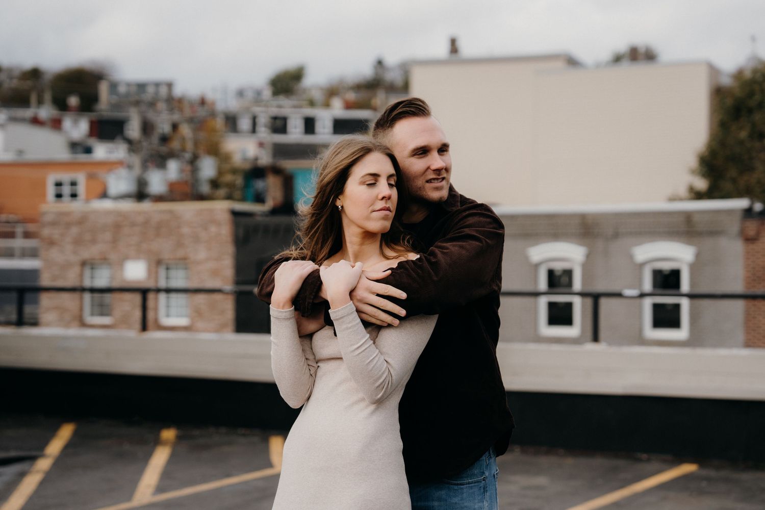 Couple enjoying a candid moment together on a rooftop with urban architecture in view.