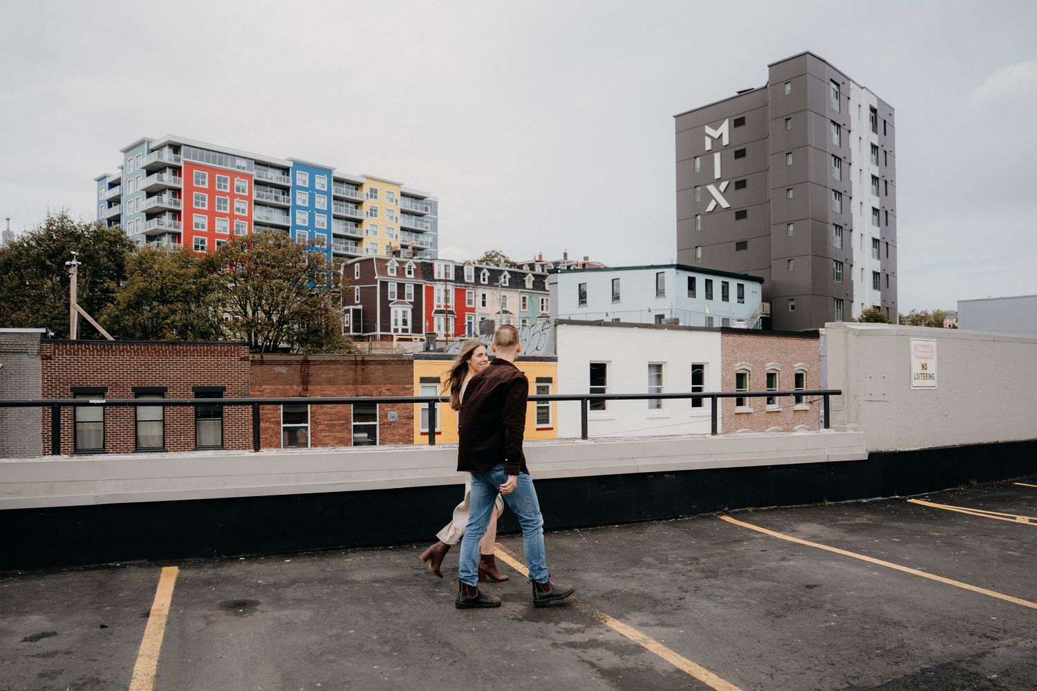 Empty rooftop parking lot with urban buildings and colorful residential towers in the background.