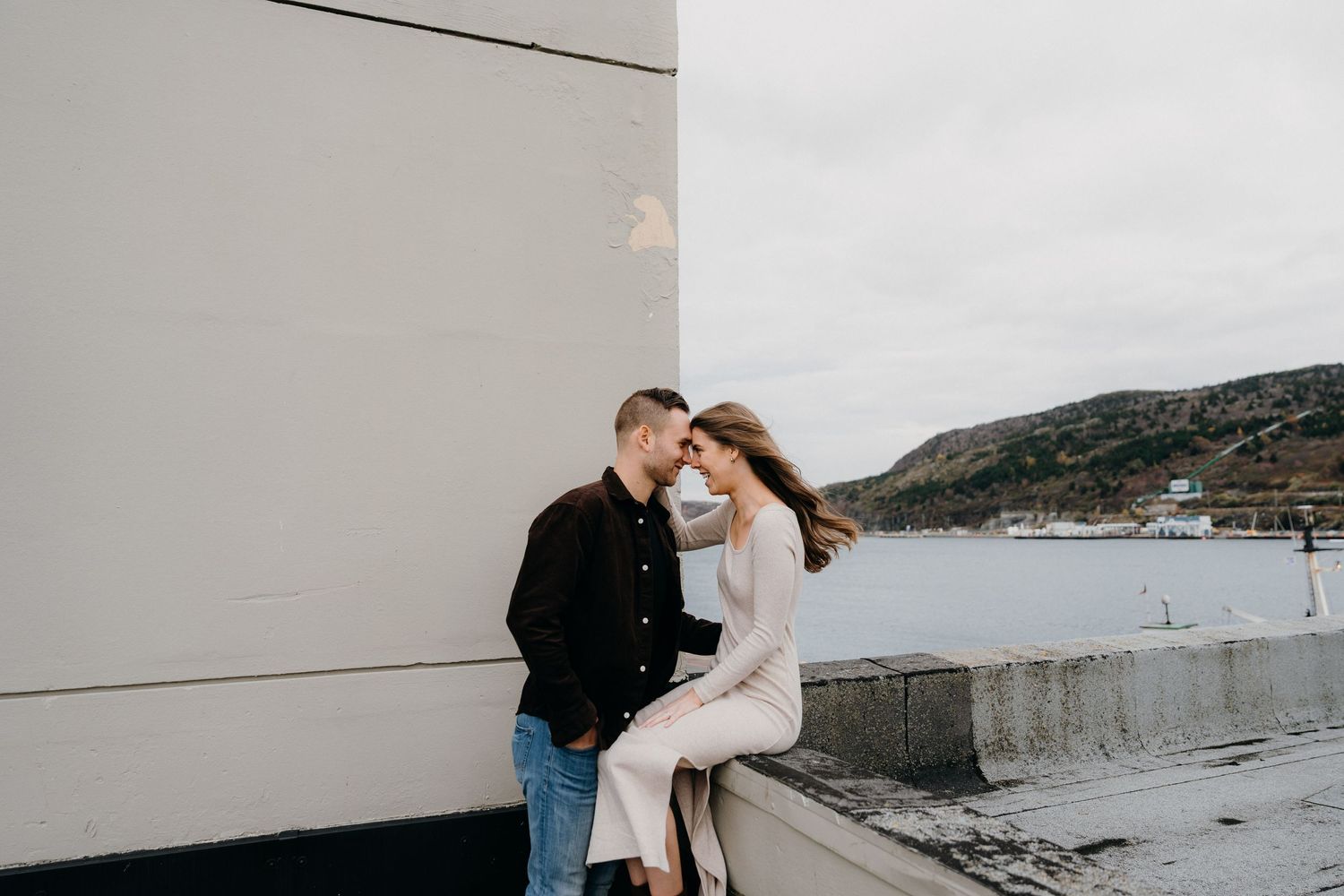 Romantic seaside photoshoot with modern architectural elements in the background.