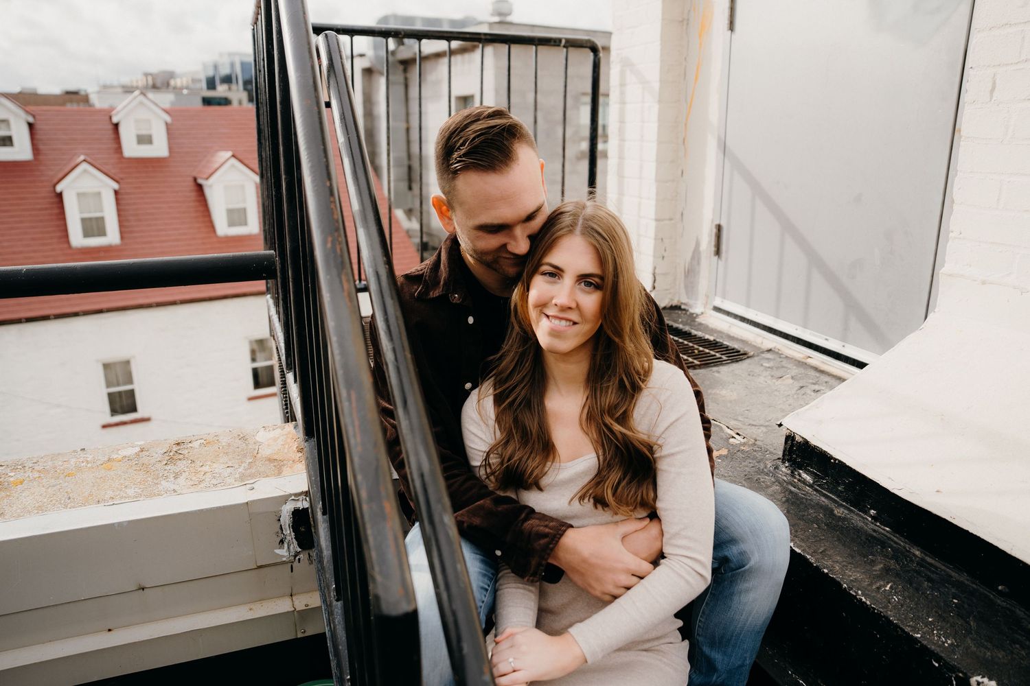Couple sitting close together on rooftop staircase in casual clothing.