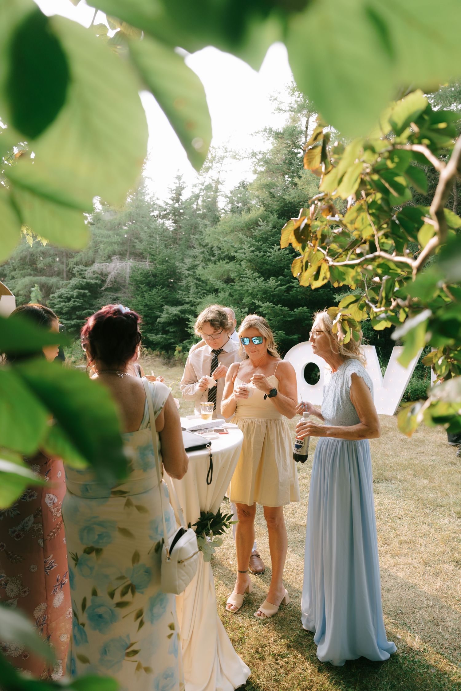 Wedding guests in formal attire mingling at an outdoor garden reception.