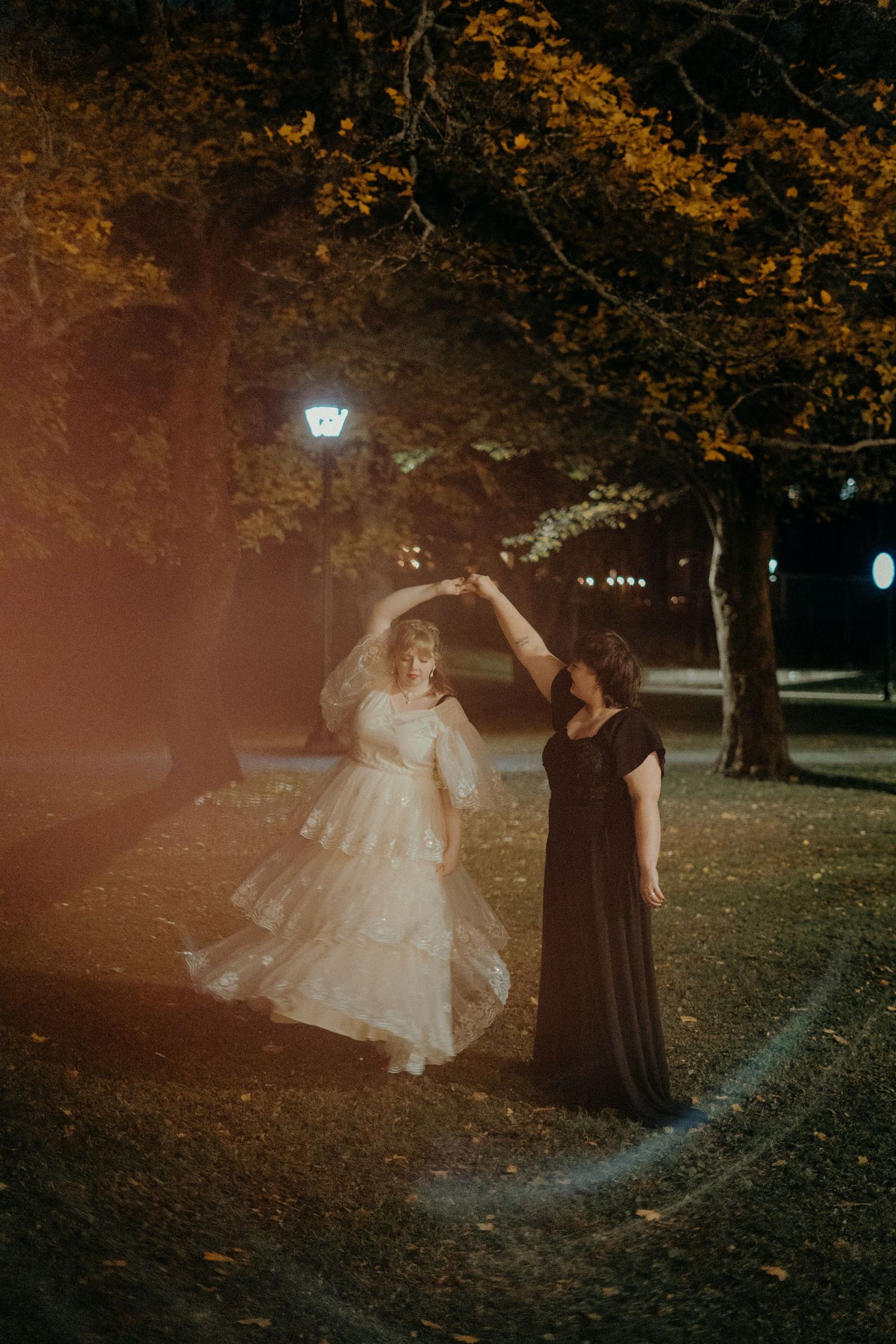 Ethereal nighttime portrait session under autumn trees with atmospheric lighting.