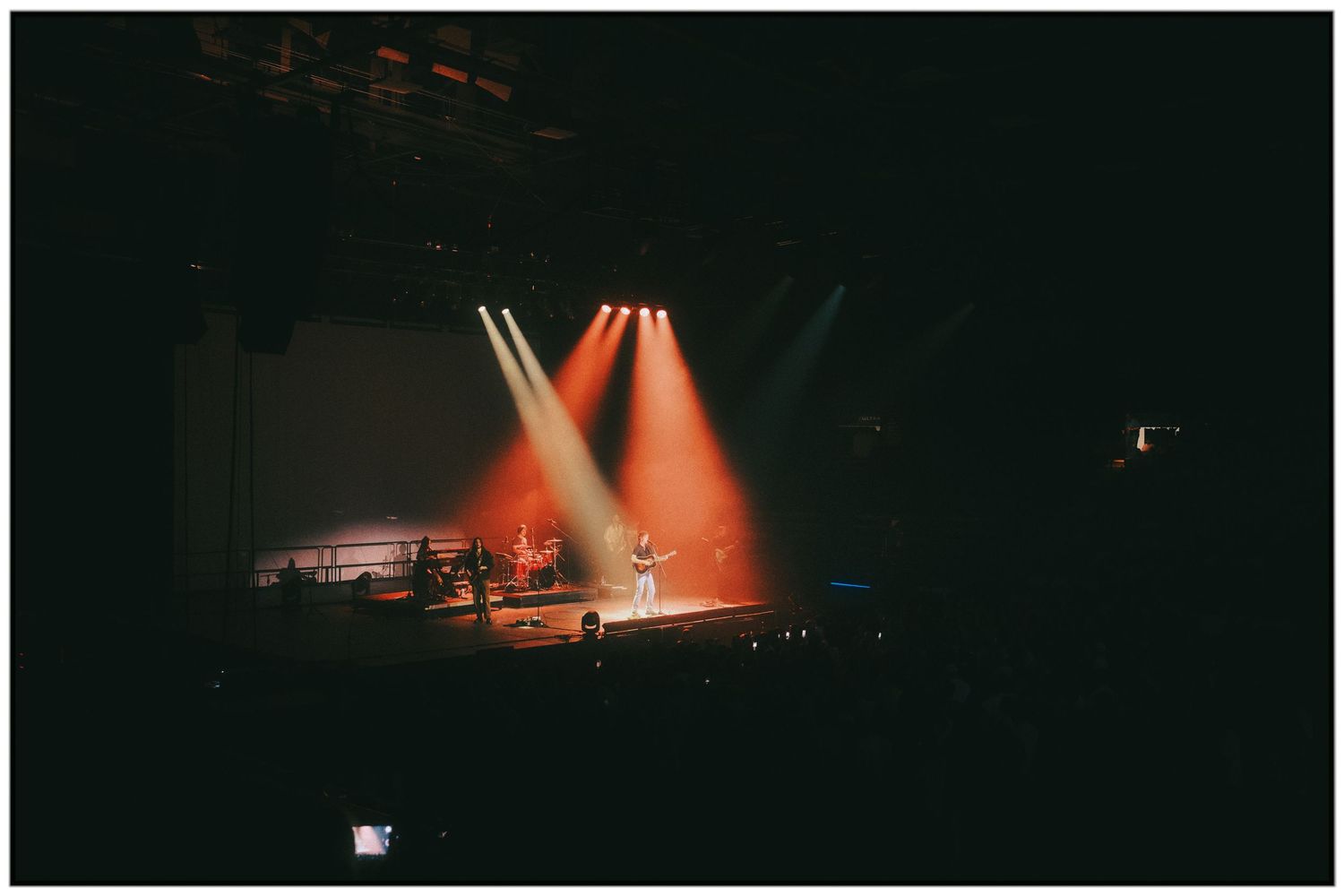 A series of concert stage photos showing dramatic red lighting and silhouetted performers during a live performance.