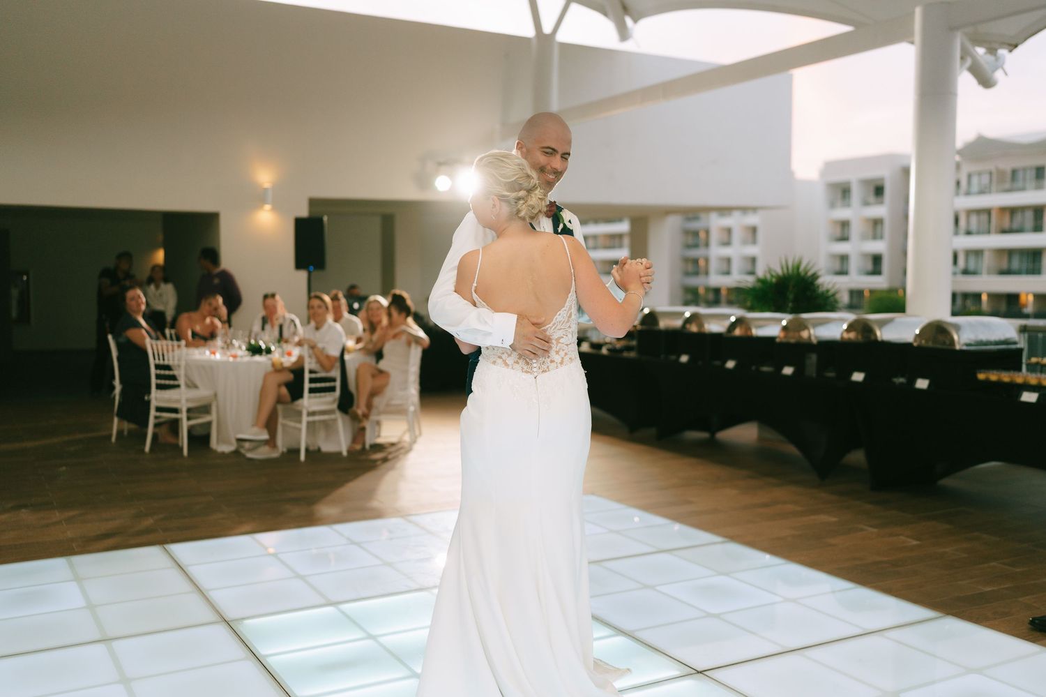 Wedding reception venue featuring an illuminated dance floor and elegant white tent setup.