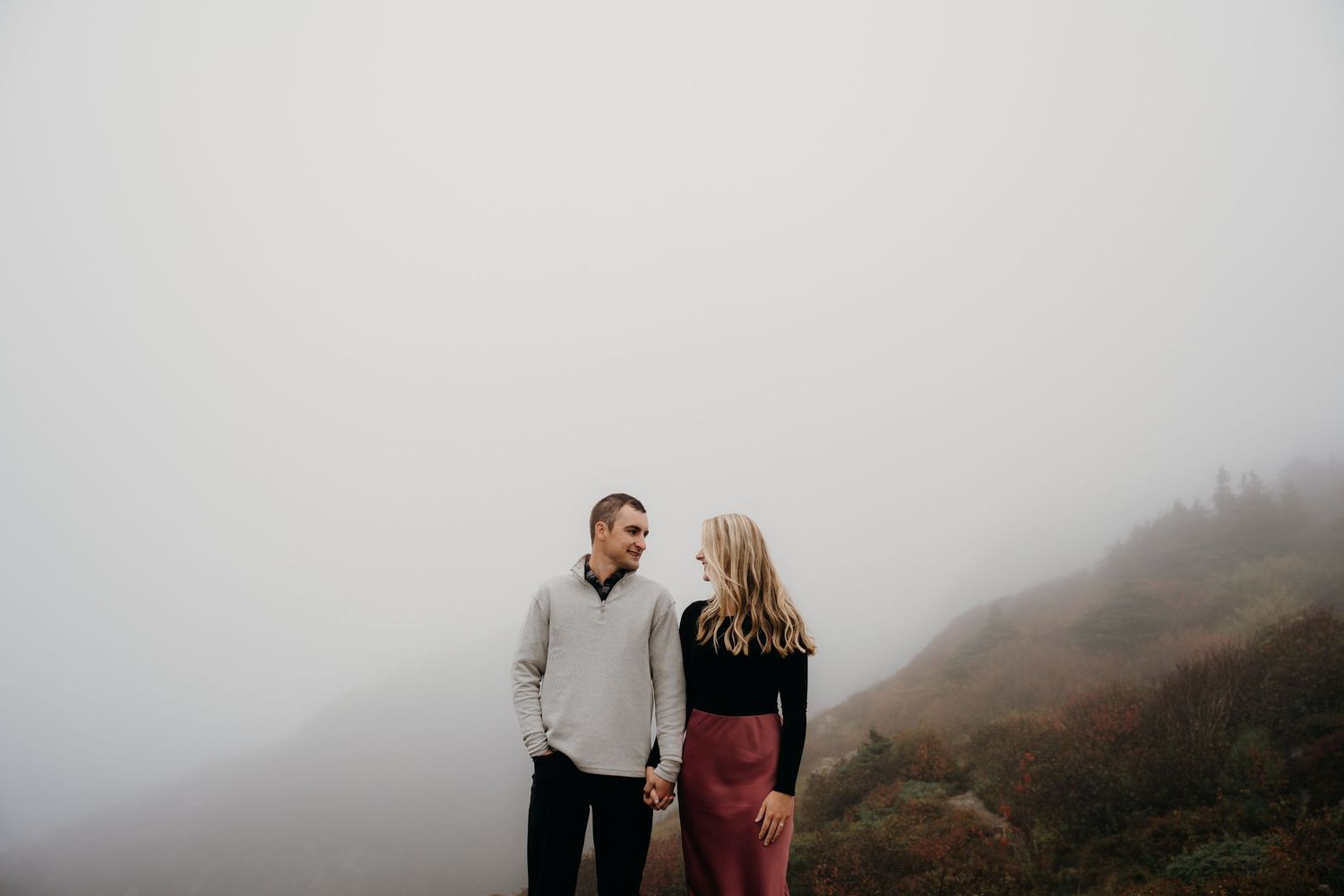 Romantic embrace captured on a foggy mountainside with moody atmosphere.