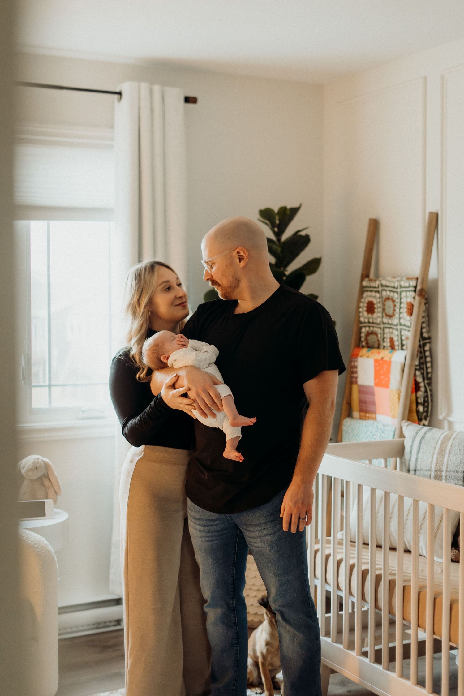 Sweet family moment with baby in minimalist nursery with white walls and crib.