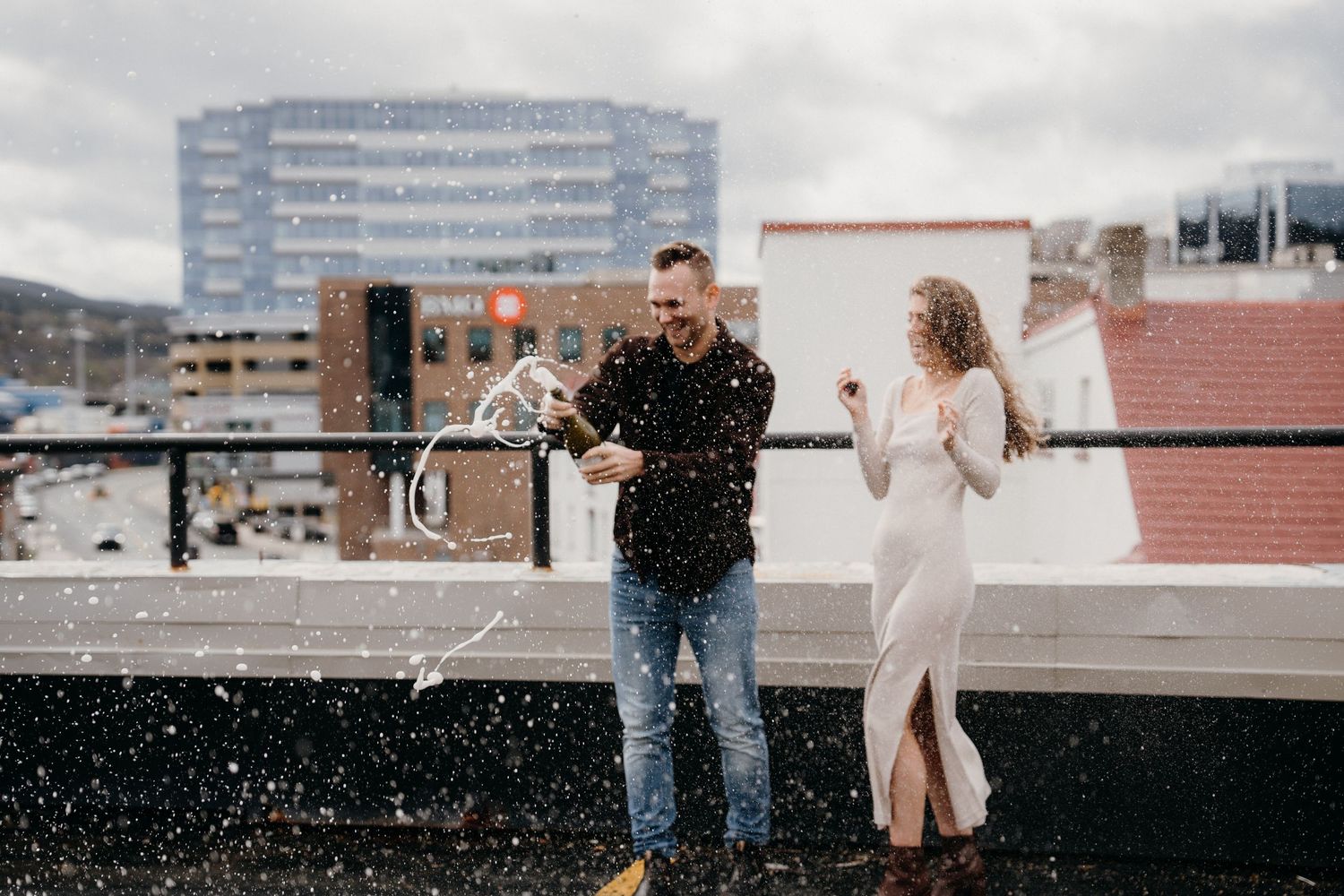 Two people sharing an emotional moment on a rooftop with urban architecture in the background.