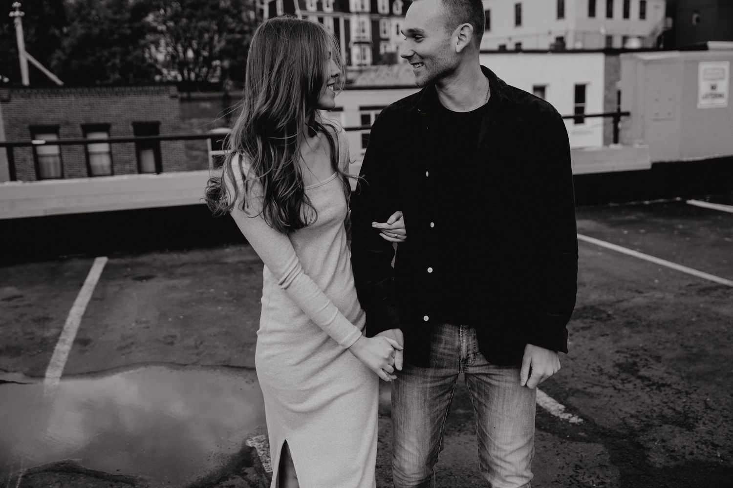 Black and white photo of a couple sharing an intimate moment against an urban backdrop.