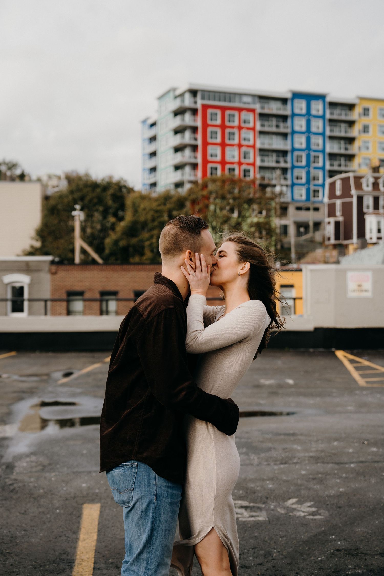 A tender moment between a couple against a backdrop of red, blue and yellow buildings.