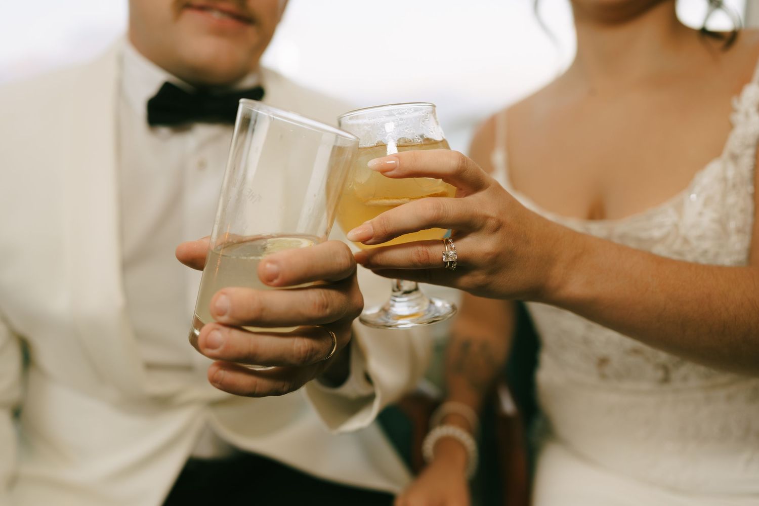 Hands holding champagne glasses clink together in a celebratory wedding toast.