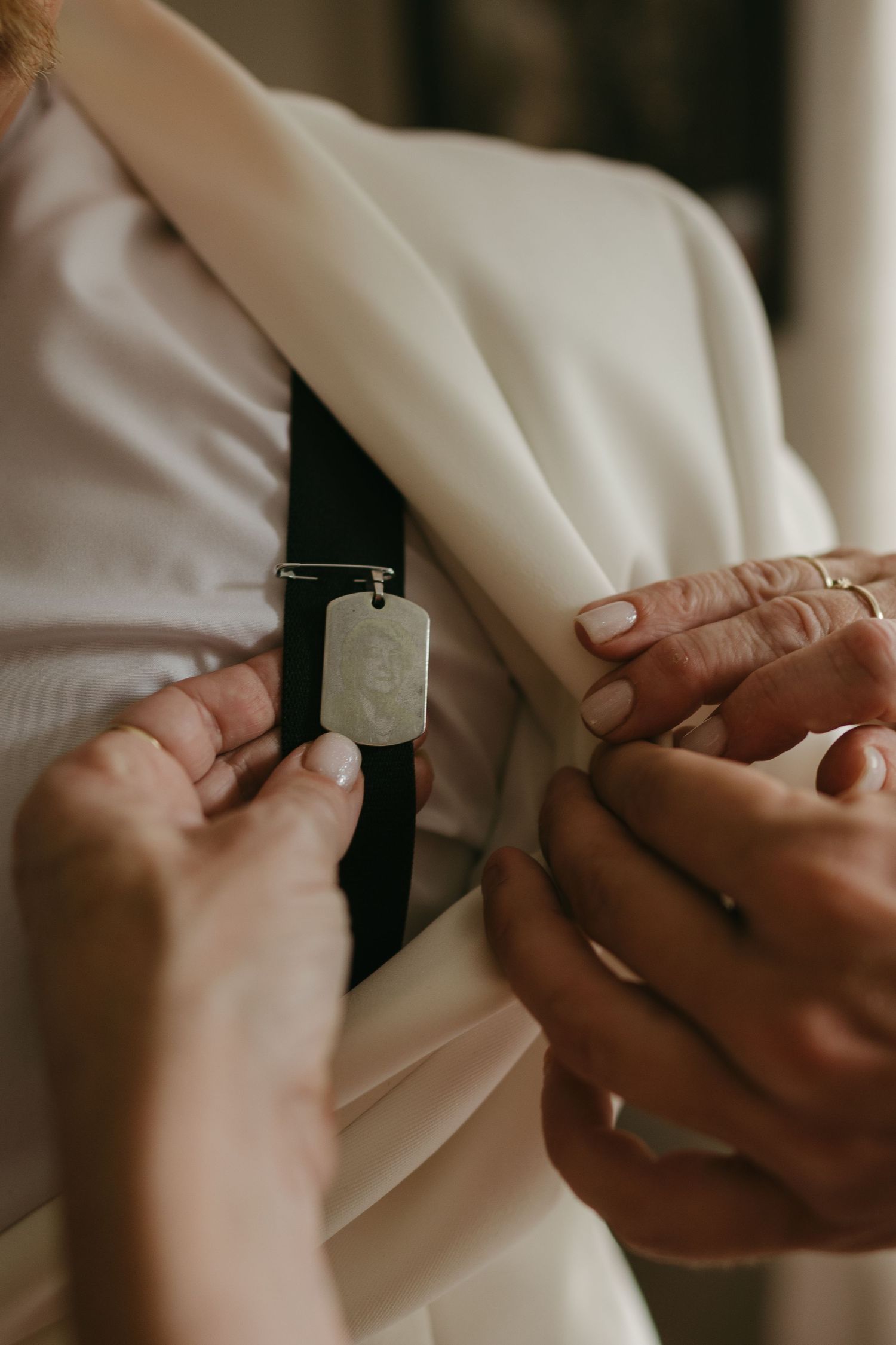Close-up of hands adjusting a black watch strap on white formal attire with manicured nails.
