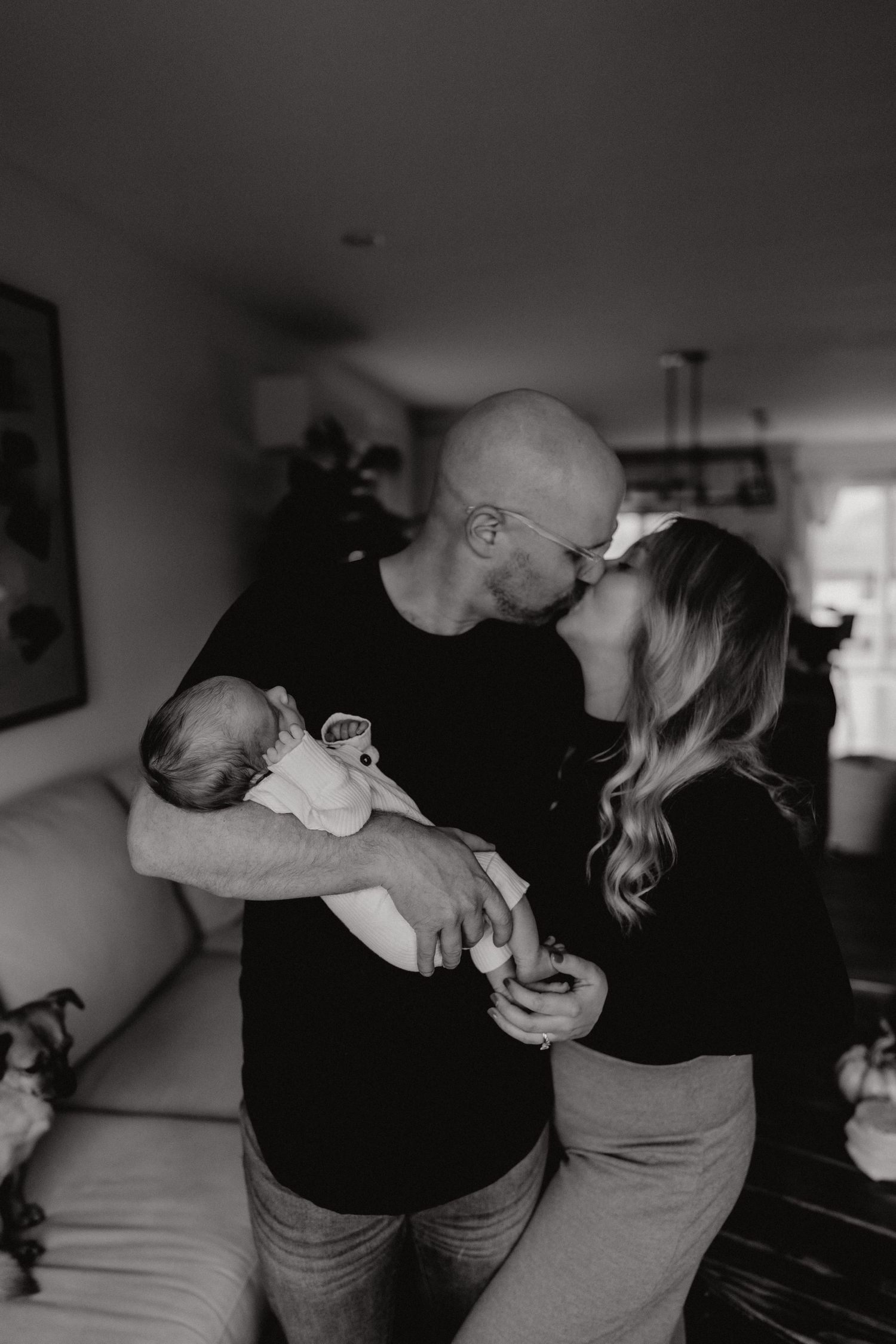 Black and white photo capturing intimate family moments with a newborn at home.