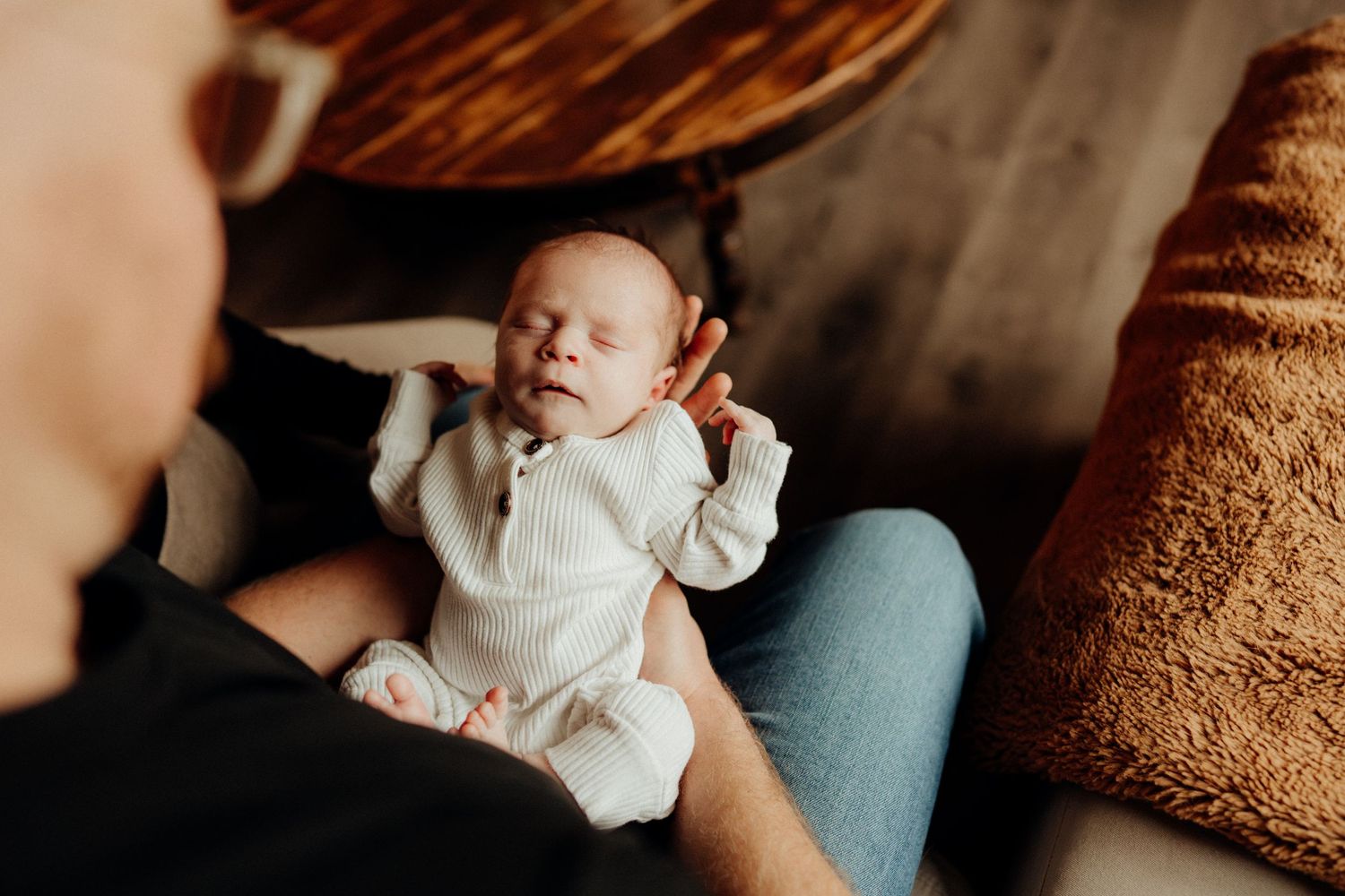 Candid lifestyle photos of parents admiring their newborn in home environment.