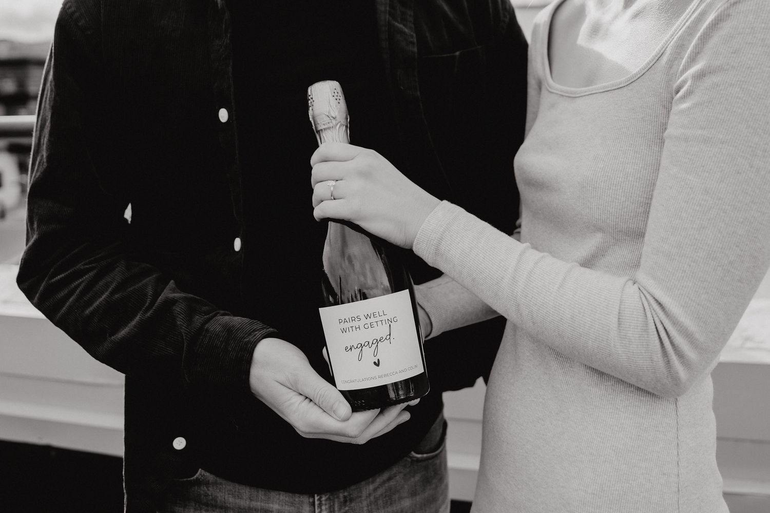 A couple sharing a special moment while holding an engagement champagne bottle.