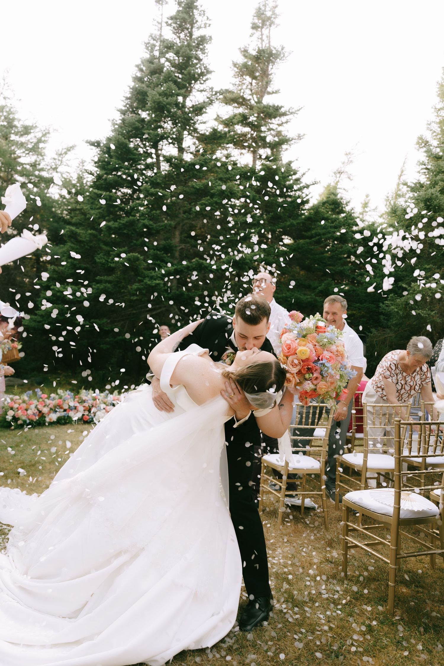 Outdoor wedding celebration with white confetti and flowing bridal gowns.