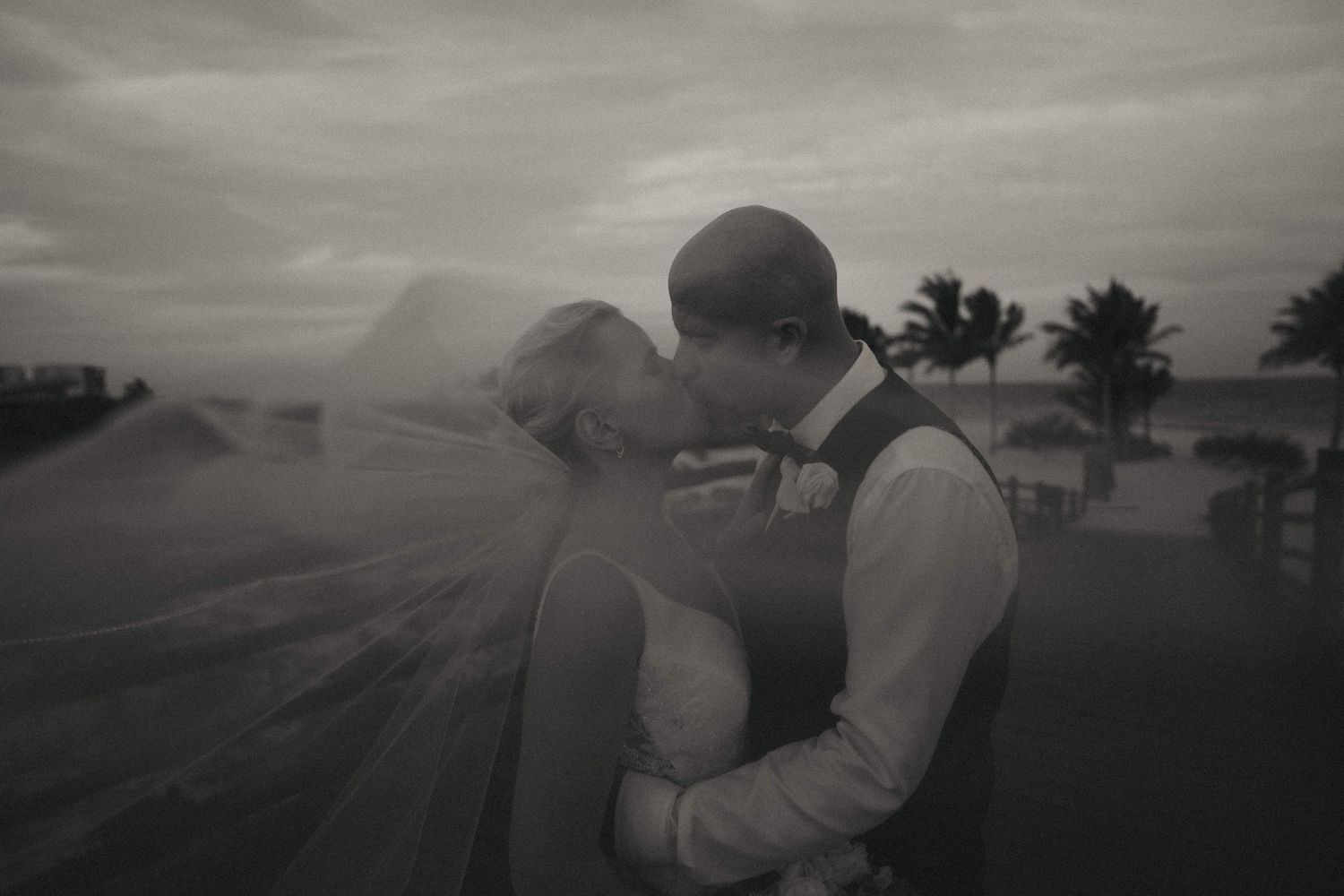 Moody black and white wedding photography against a dramatic coastal landscape.