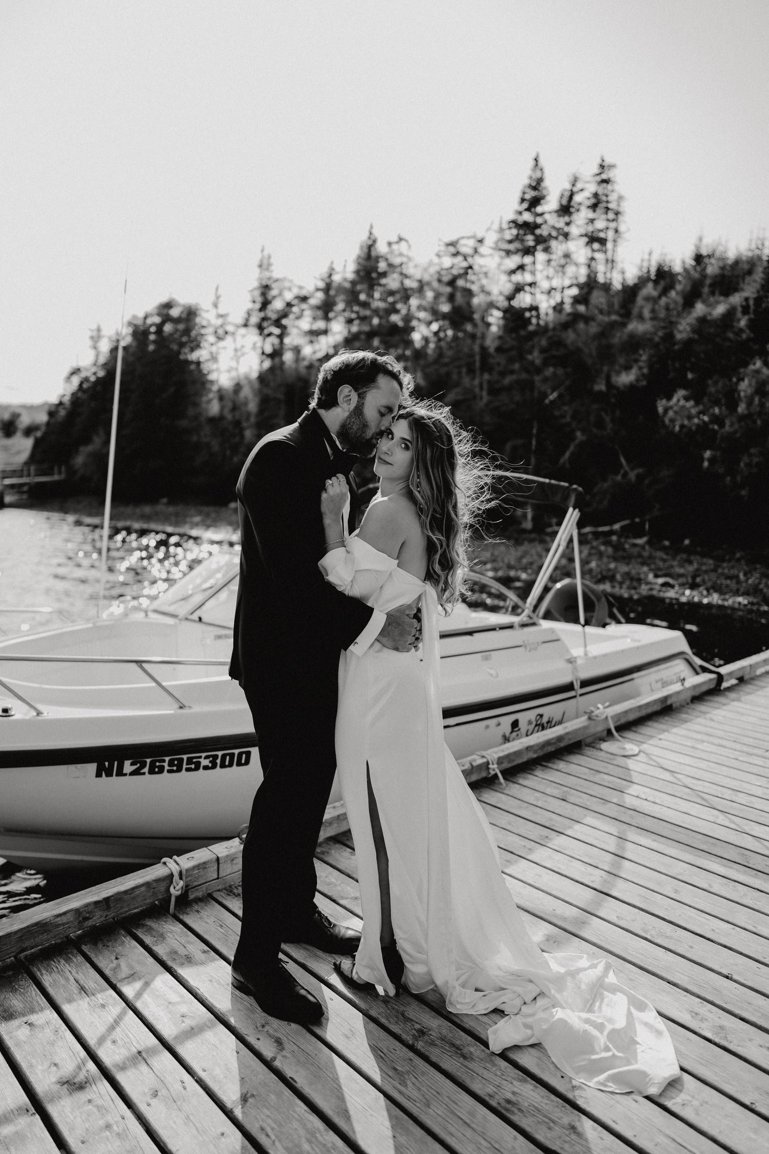 A romantic wedding moment on a dock with boats in the background.