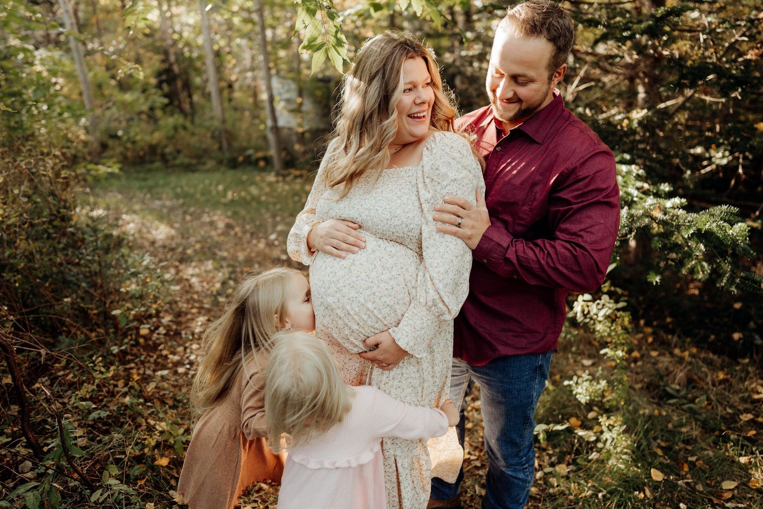 Embracing family members share tender moments in a sunlit forest clearing.