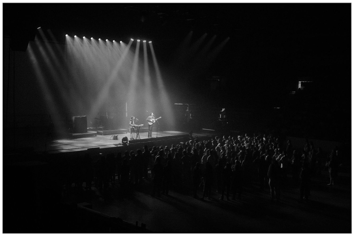 Black and white concert photos show dramatic stage lighting and silhouettes of performers during a live music performance.