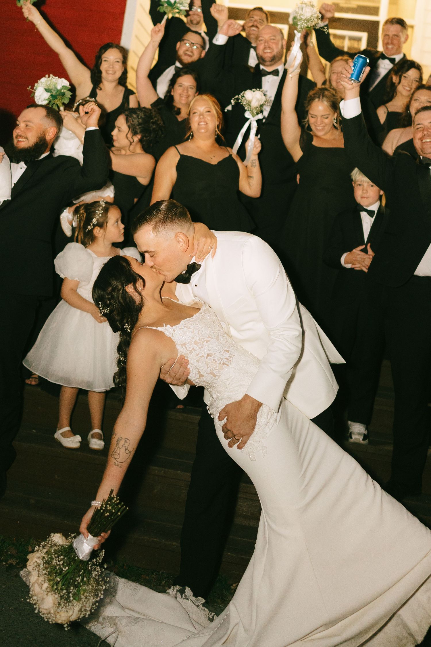 A couple performs a dramatic dip during their wedding dance while guests look on from the background.