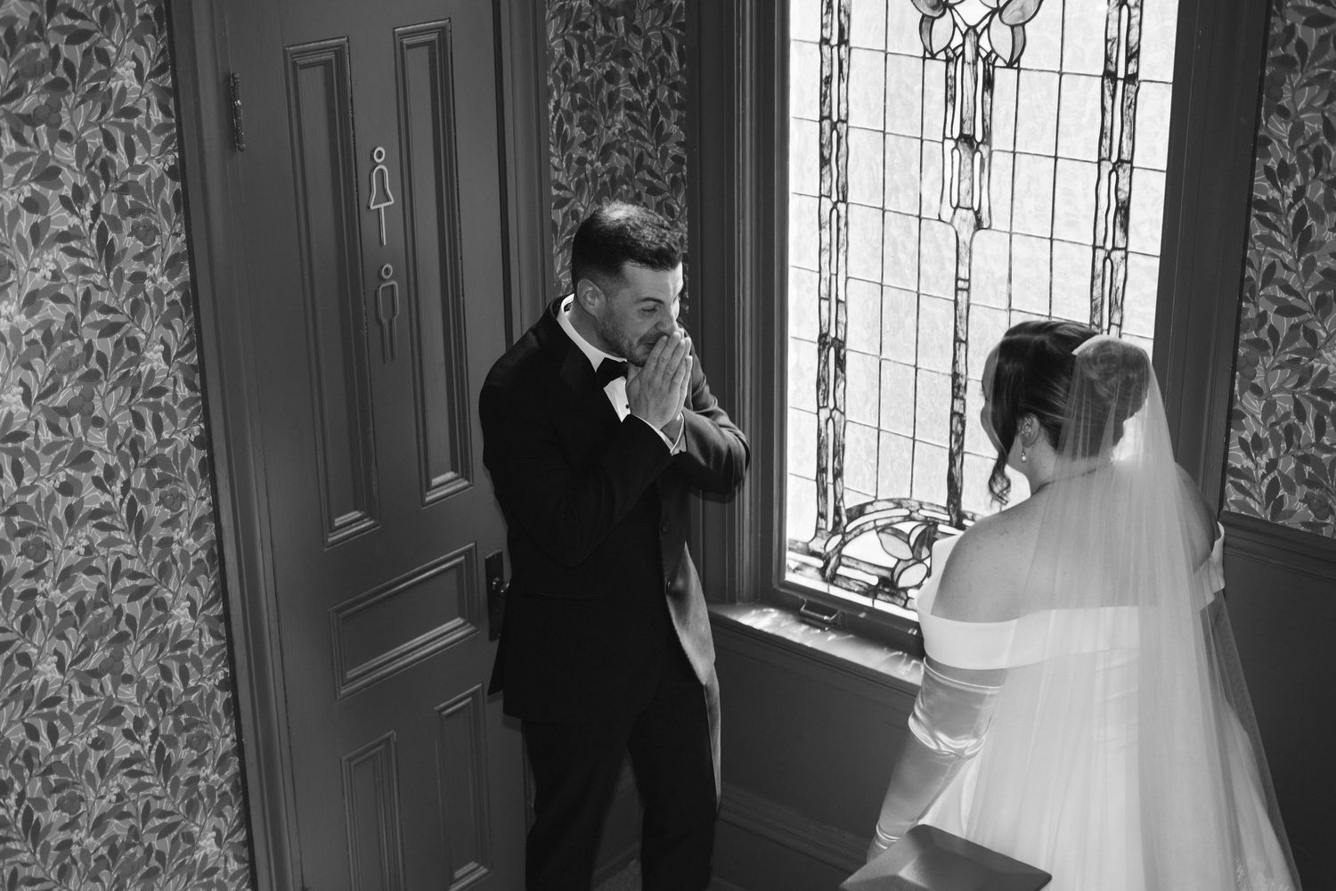 Wedding moment captured near stained glass window in historic setting.