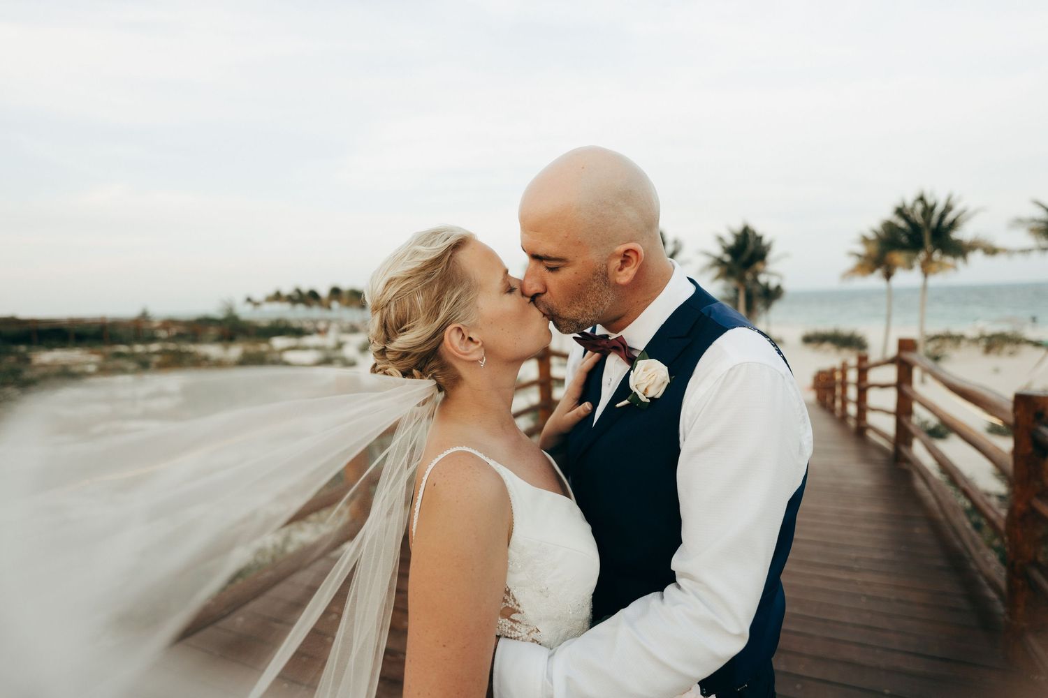 An intimate moment shared between newlyweds on a wooden boardwalk by the ocean.
