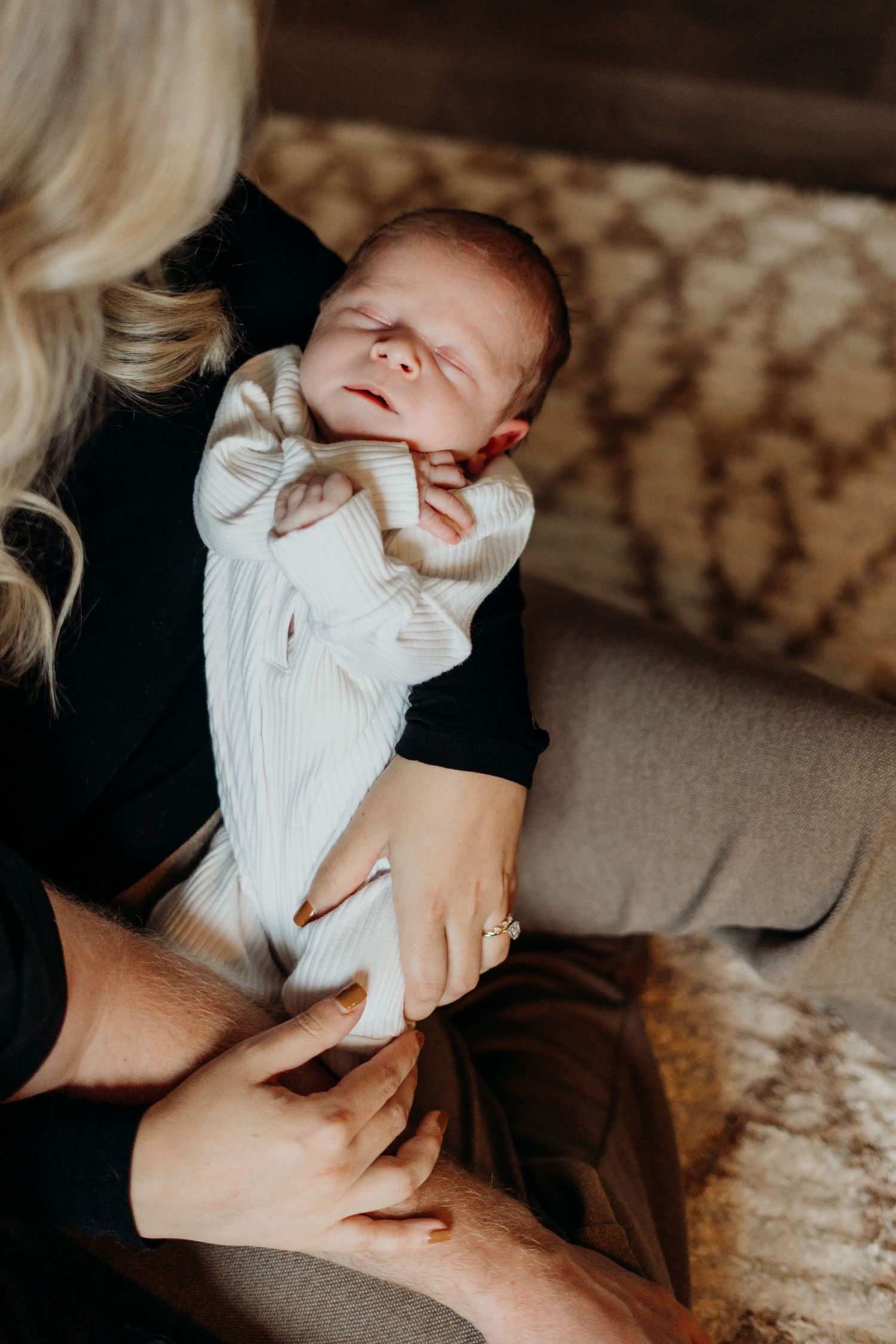 Intimate lifestyle photography session with white knit clothing against dark background.