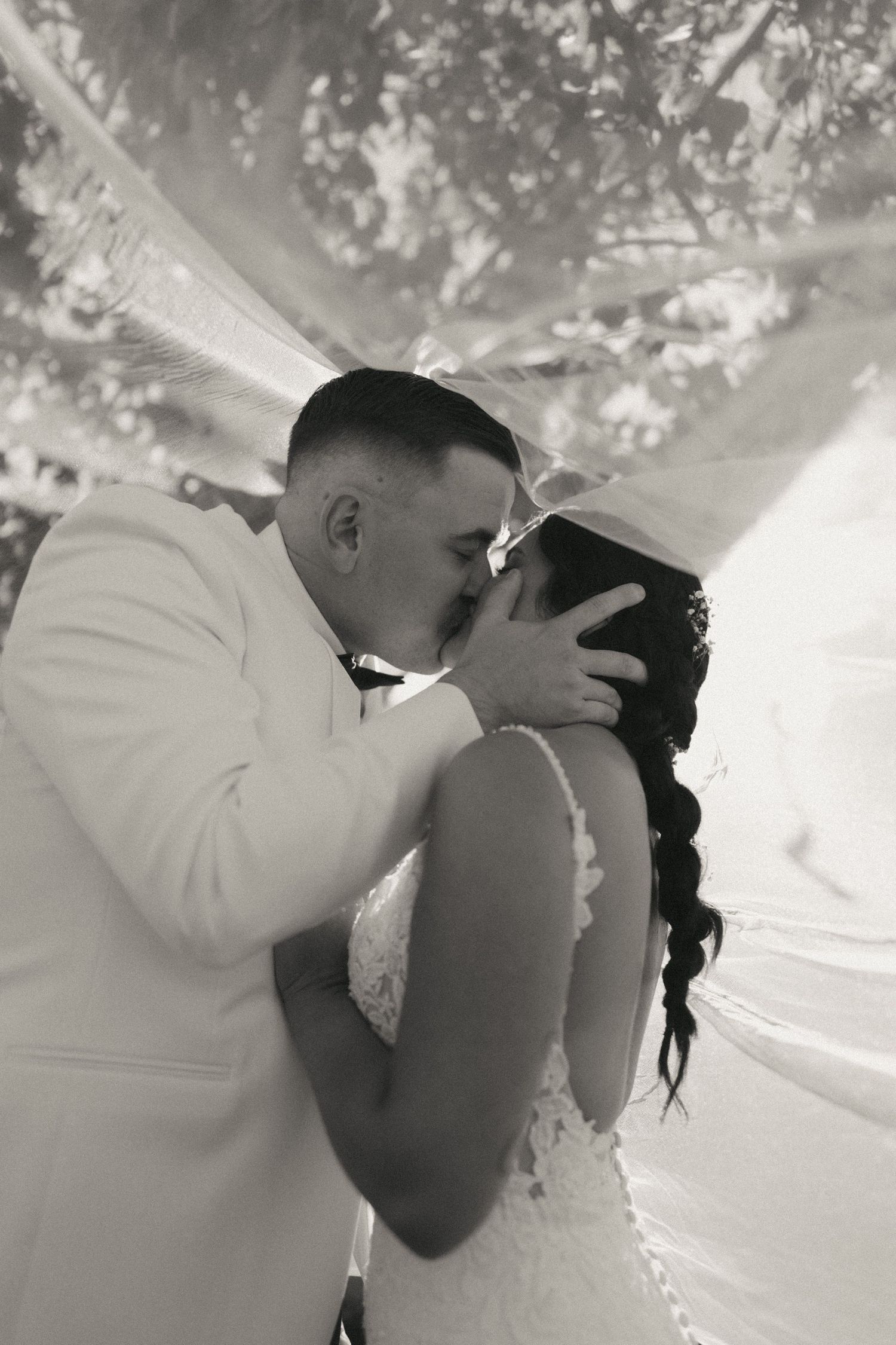 A romantic black and white photo sequence showing a couple in wedding attire sharing tender kisses outdoors.